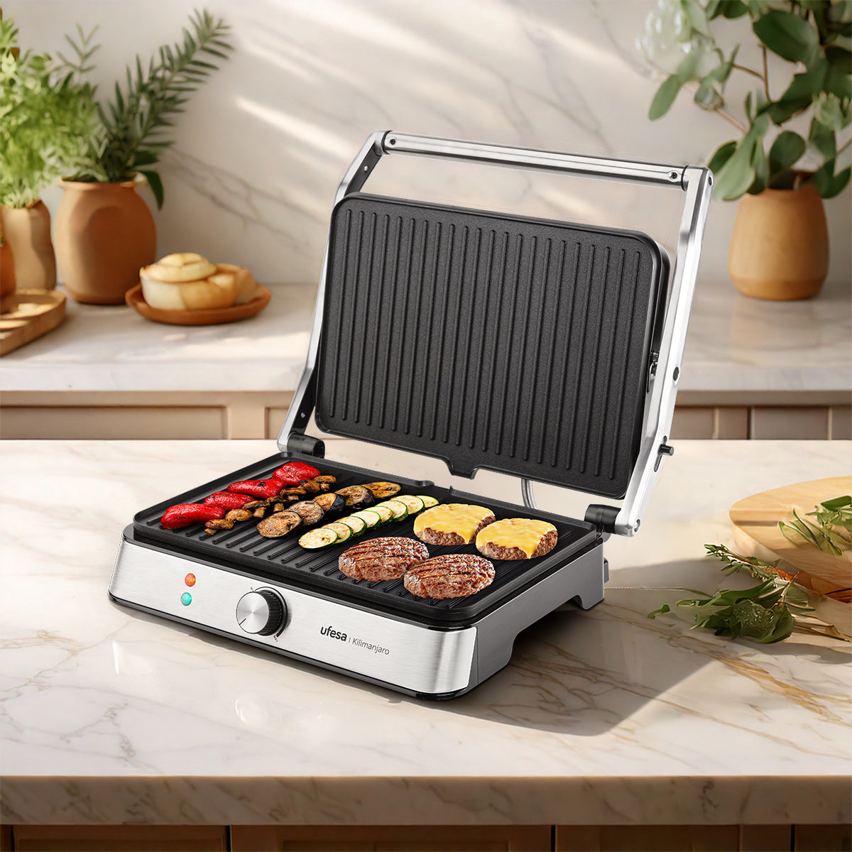 Parrilla eléctrica abierta con comida cocinándose en la plancha, con encimera de mármol blanco.