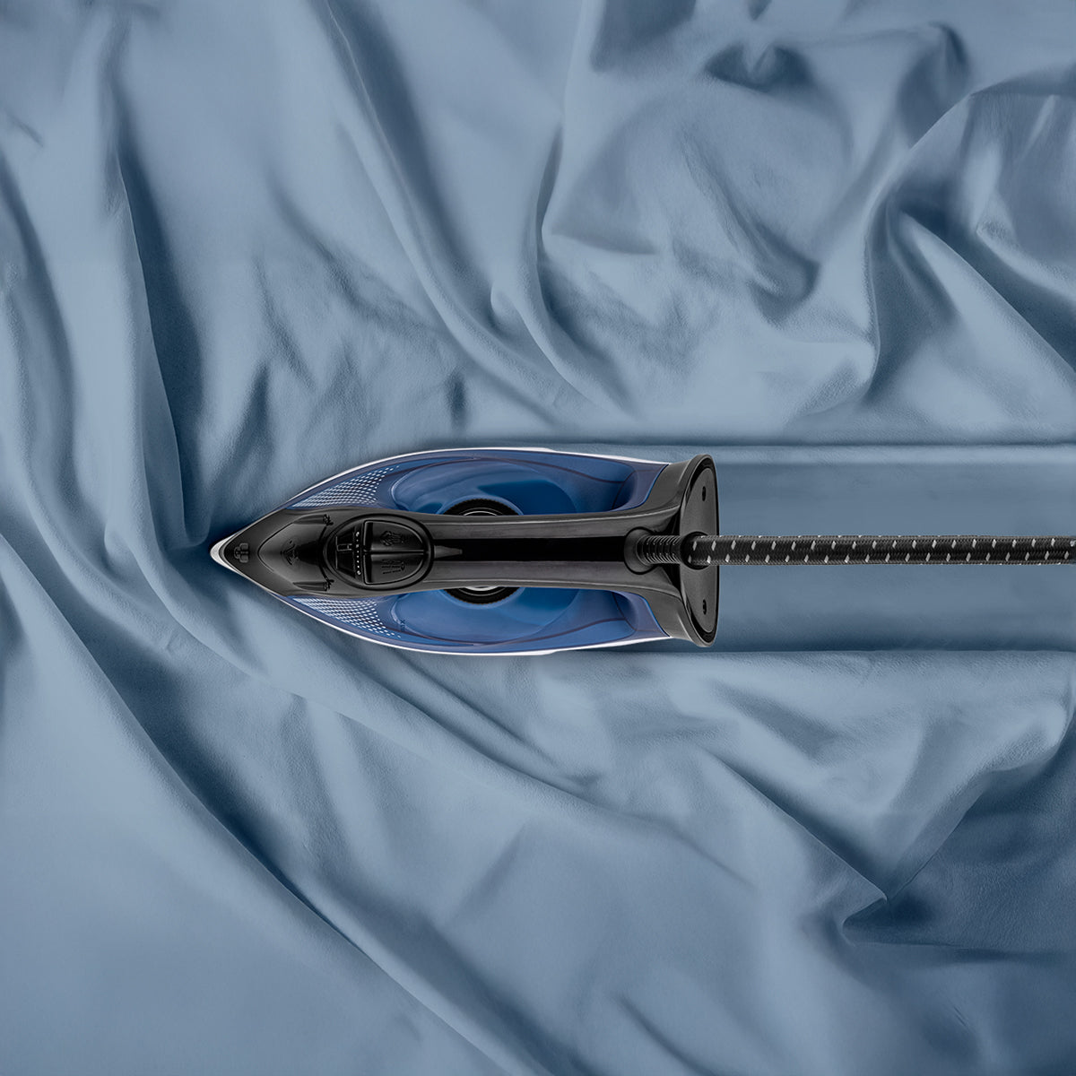 Ferro da stiro su tessuto blu. Il ferro è nero e blu.