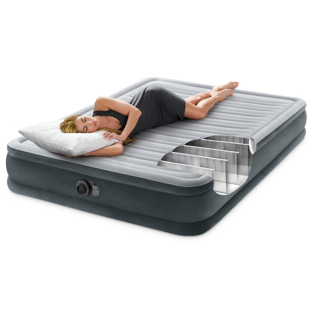 Une femme est allongée sur un matelas gonflable gris avec un oreiller. Une coupe montre la structure interne. Elle porte une robe grise.