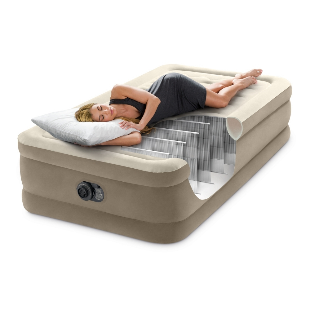 Une femme est allongée sur un matelas gonflable beige, vue en coupe. Elle tient un oreiller, fond blanc.