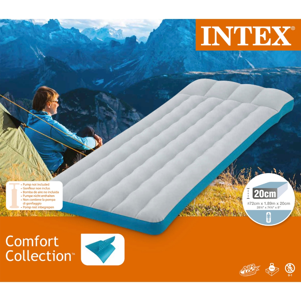 Une personne assise près d'un matelas gonflable bleu et blanc devant des montagnes.