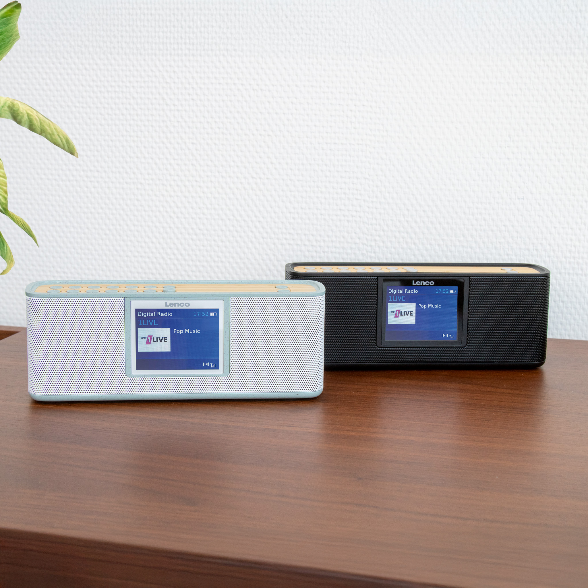 Zwei Digitalradios auf einem Holztisch. Eines ist weiß, das andere schwarz.