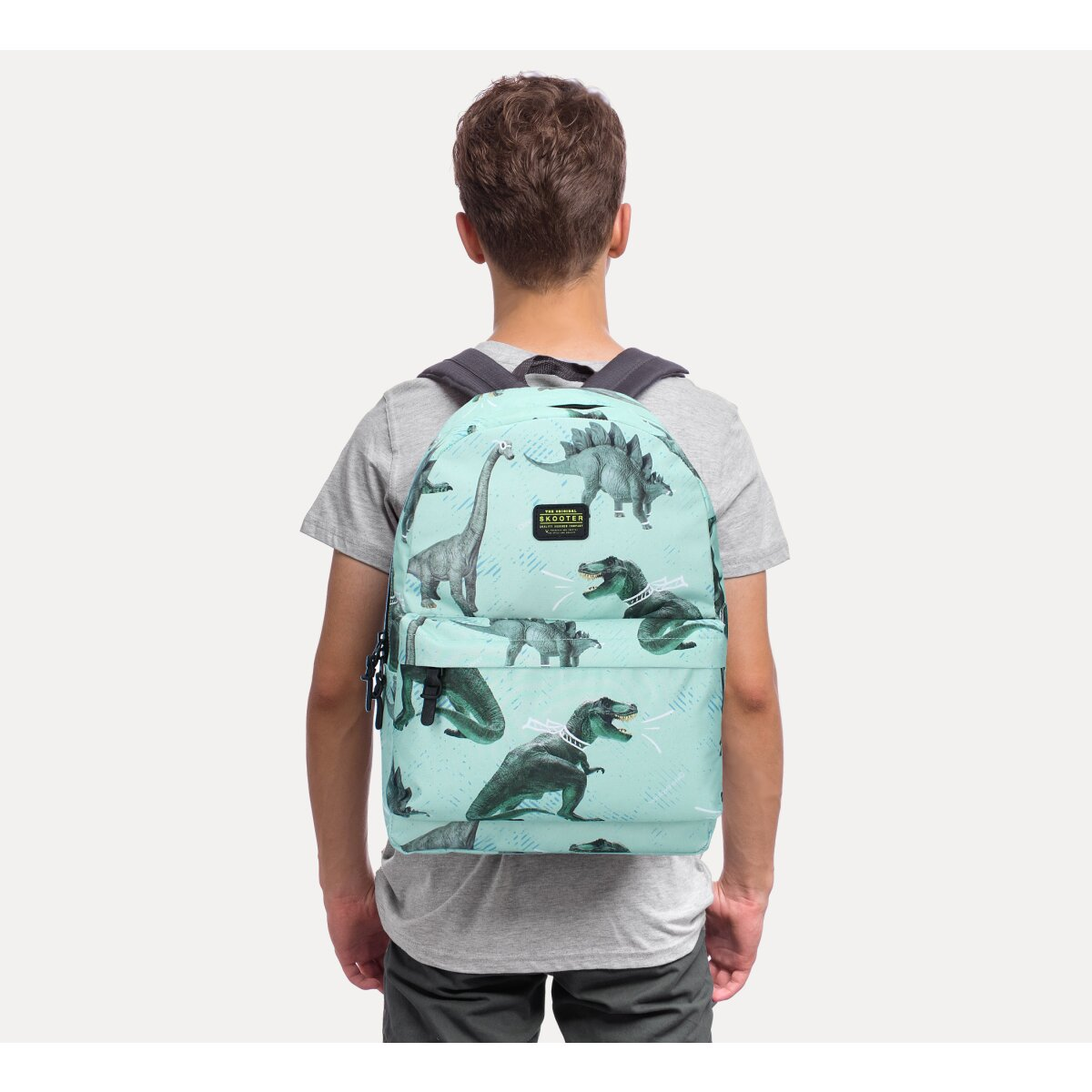 Ein Kind mit einem Rucksack mit Dinosaurier-Mustern.