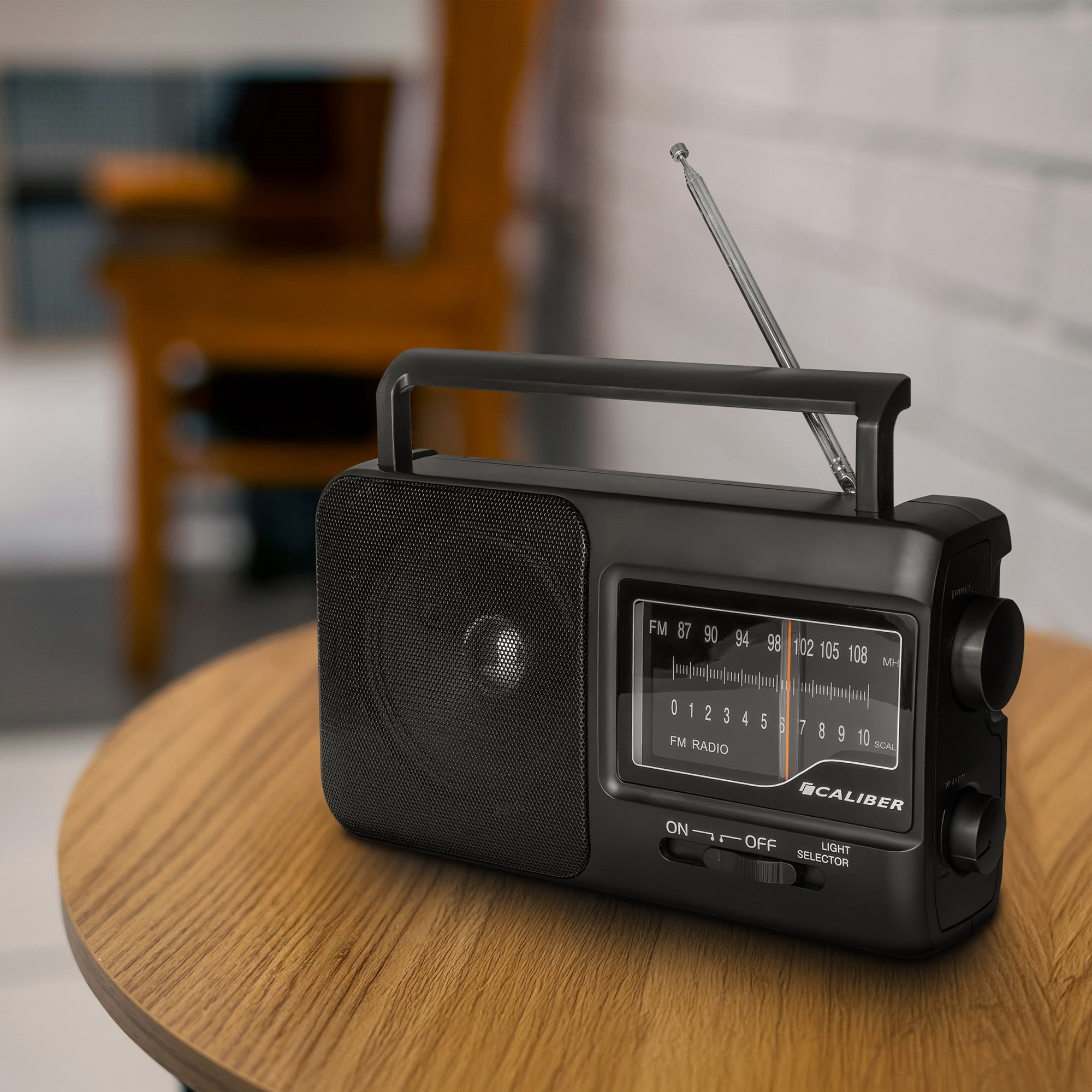 Black retro radio on a wooden table. Antenna extended, controls visible. Blurred background.