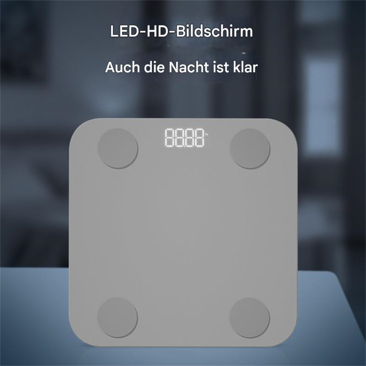 Graue, quadratische Smart-Waage mit Digitalanzeige auf einem Tisch. Deutscher Text.