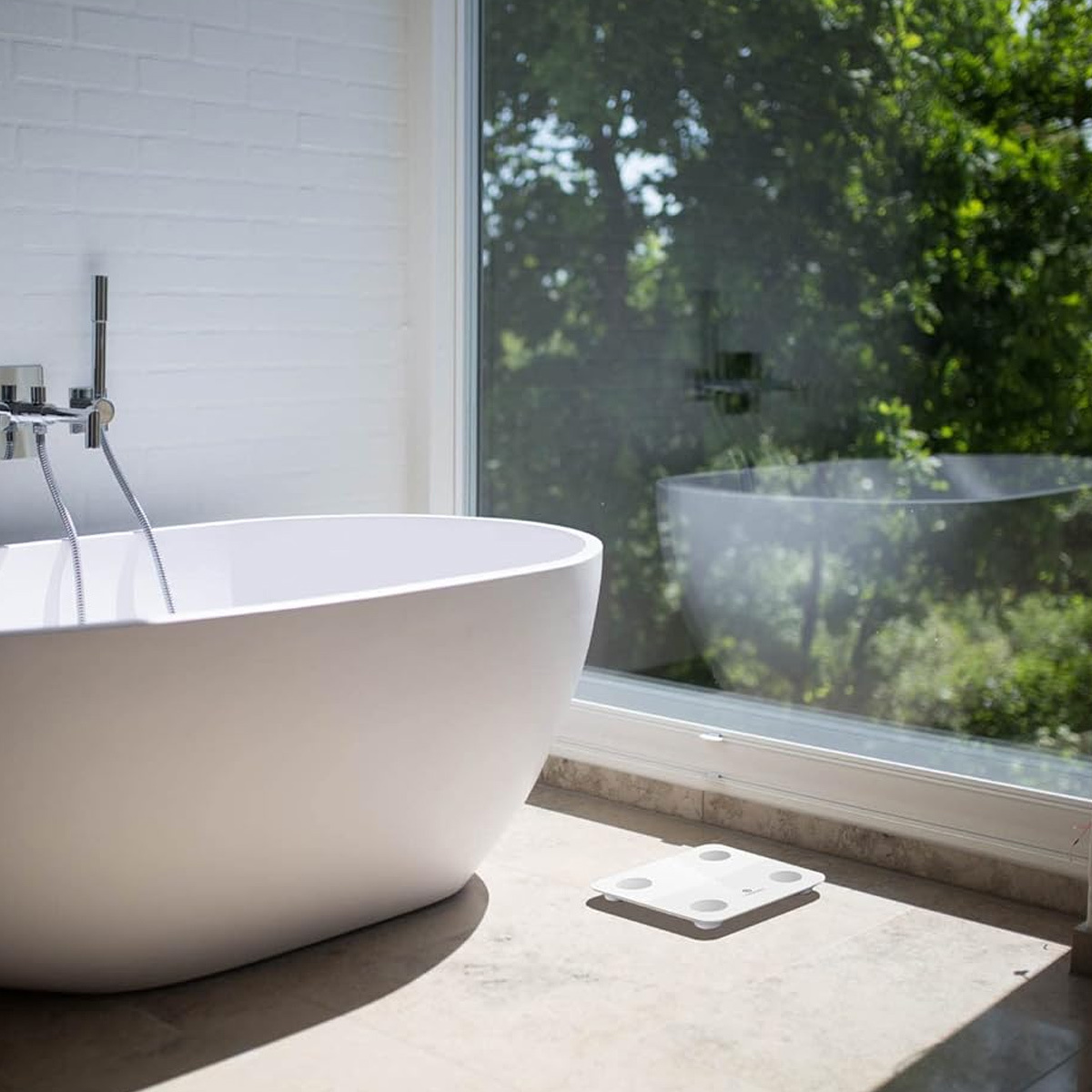 Badezimmer mit weißer Badewanne, Waage und Fenster.