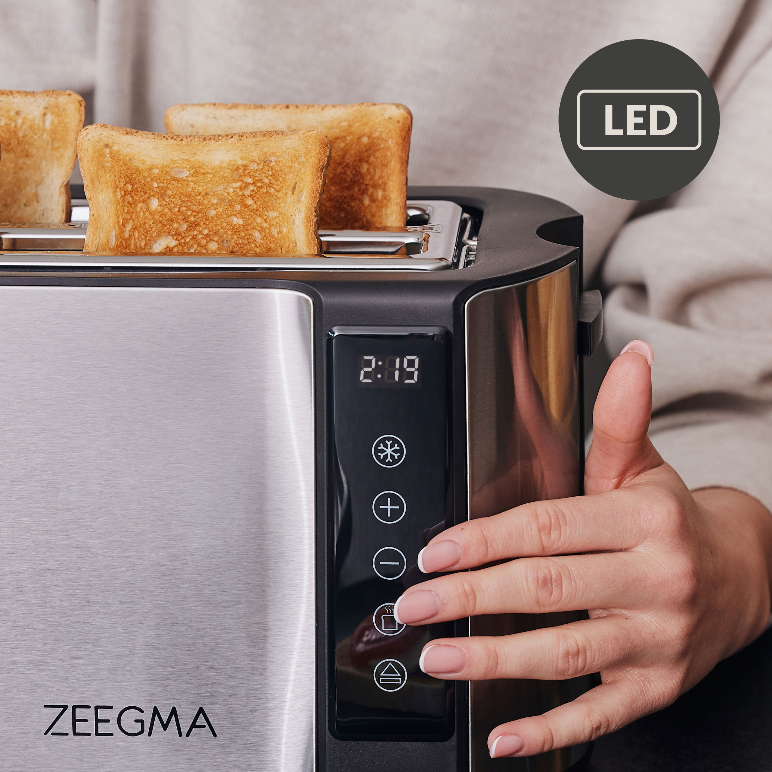 Broodrooster met twee sneetjes toast. Een hand bedient het bedieningspaneel met een LED-licht.