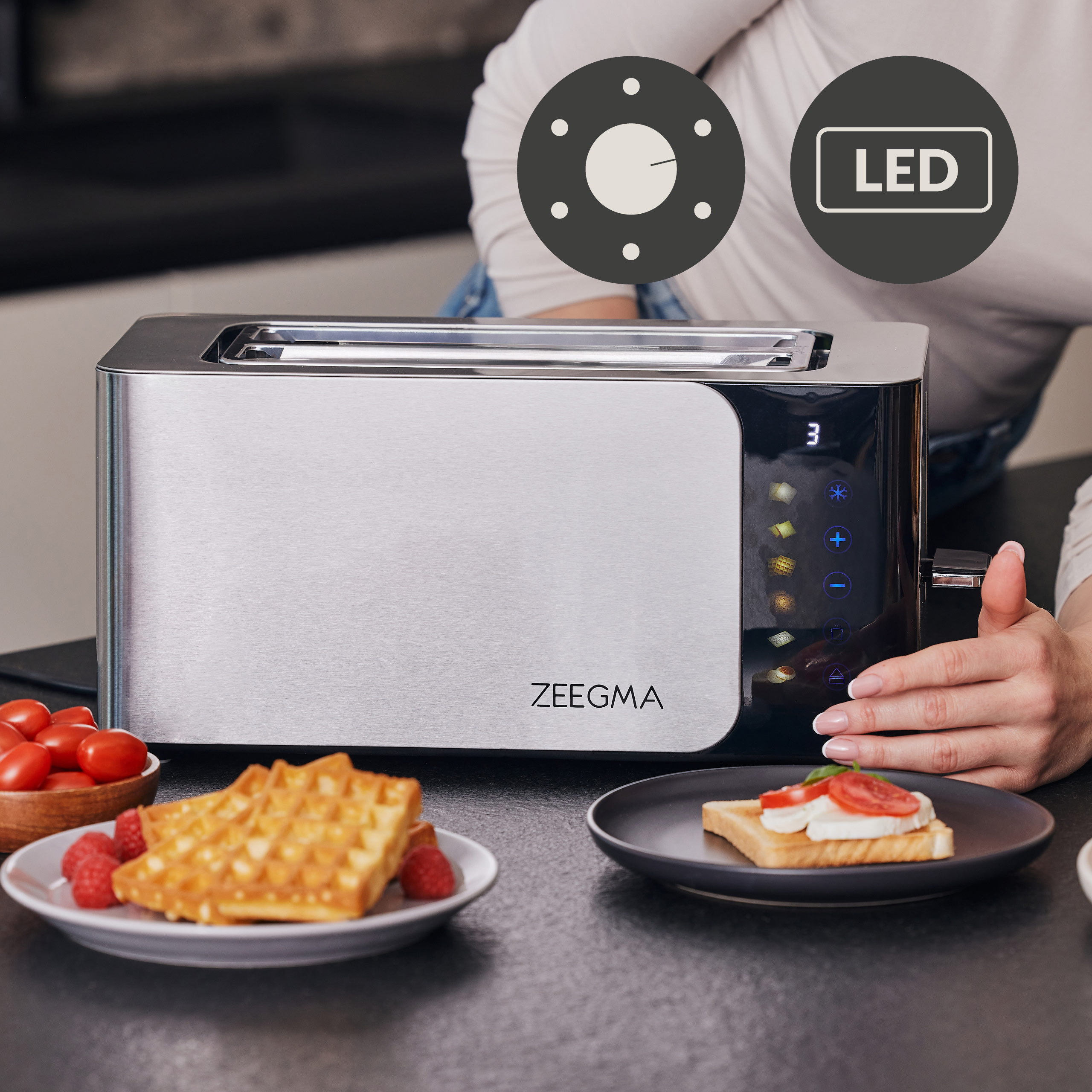 Zilveren broodrooster met knoppen, wafels en een toastje met tomaat.