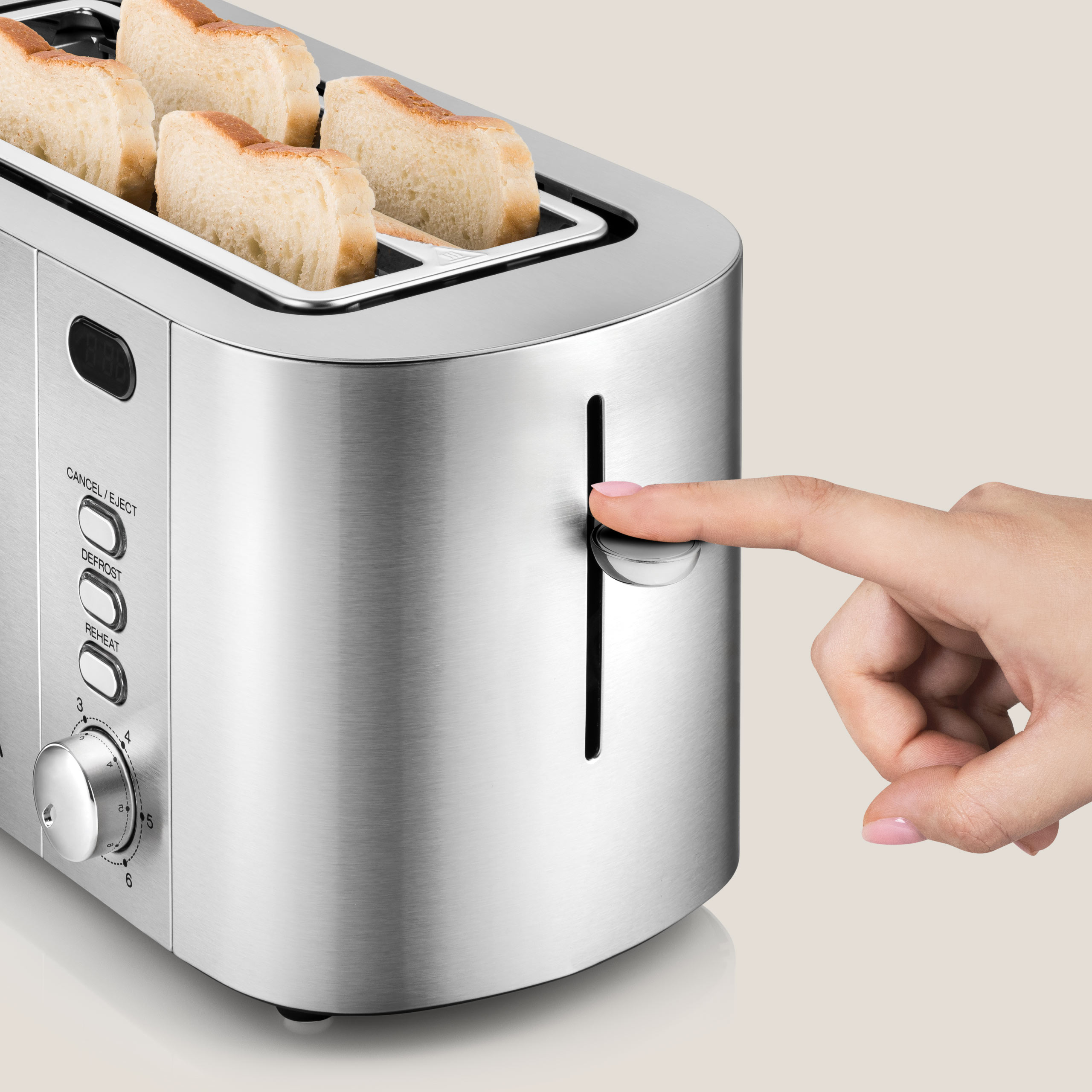 Srebrny toster z kromkami chleba. Ręka naciska dźwignię, aby opiec chleb.