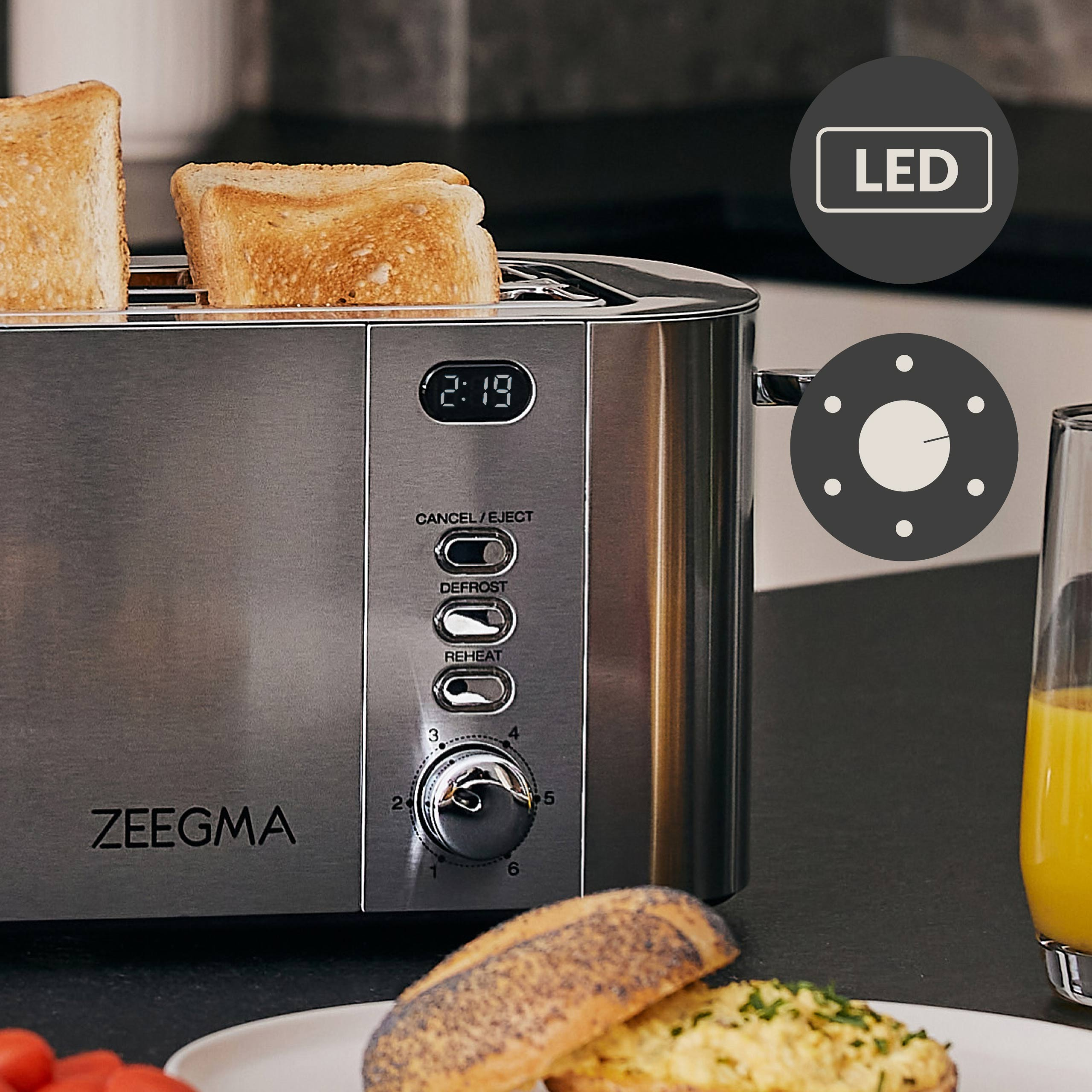 Toster ze stali nierdzewnej z widocznymi tostami i ustawieniami. Obok sok pomarańczowy i talerz.