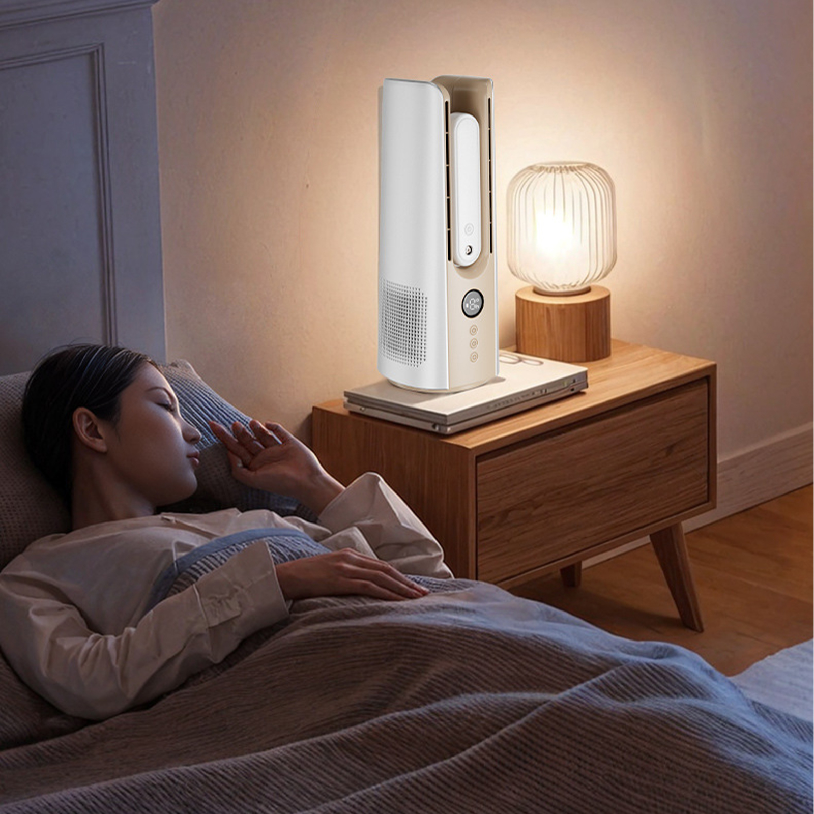 Eine schlafende Frau im Bett, neben einem Nachttisch mit Ventilator und Lampe. Der Raum ist dunkel.