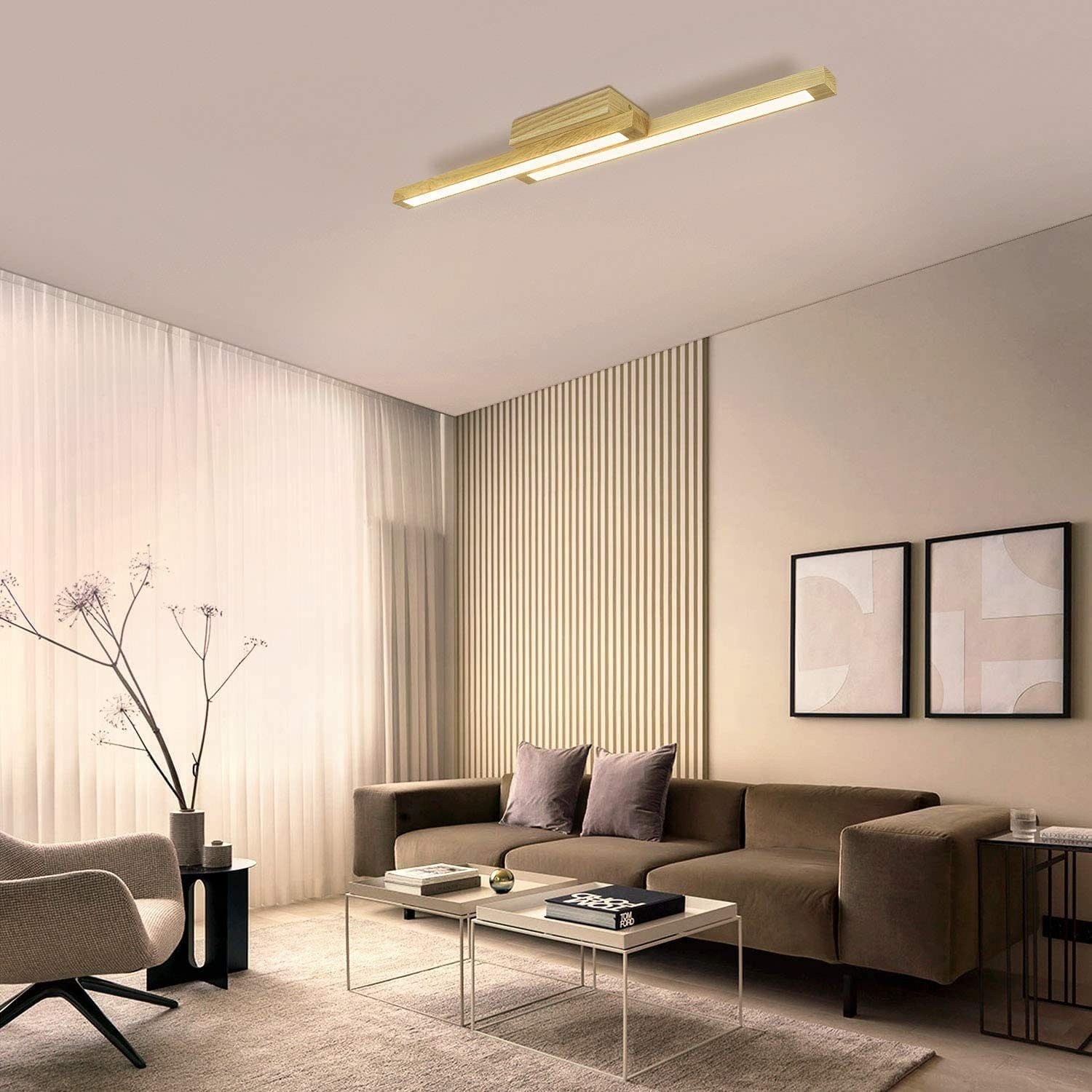 Soggiorno con divano marrone, due quadri e una lampada da soffitto in legno.