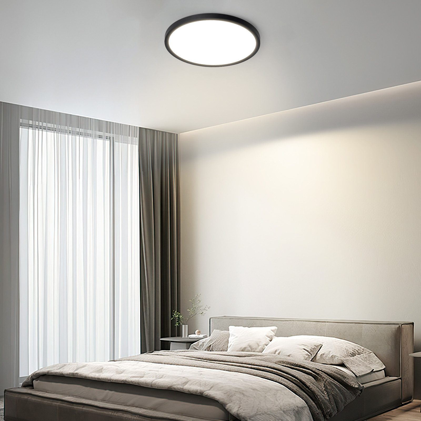 Una camera da letto con una luce a soffitto rotonda, un letto, tende e una finestra.