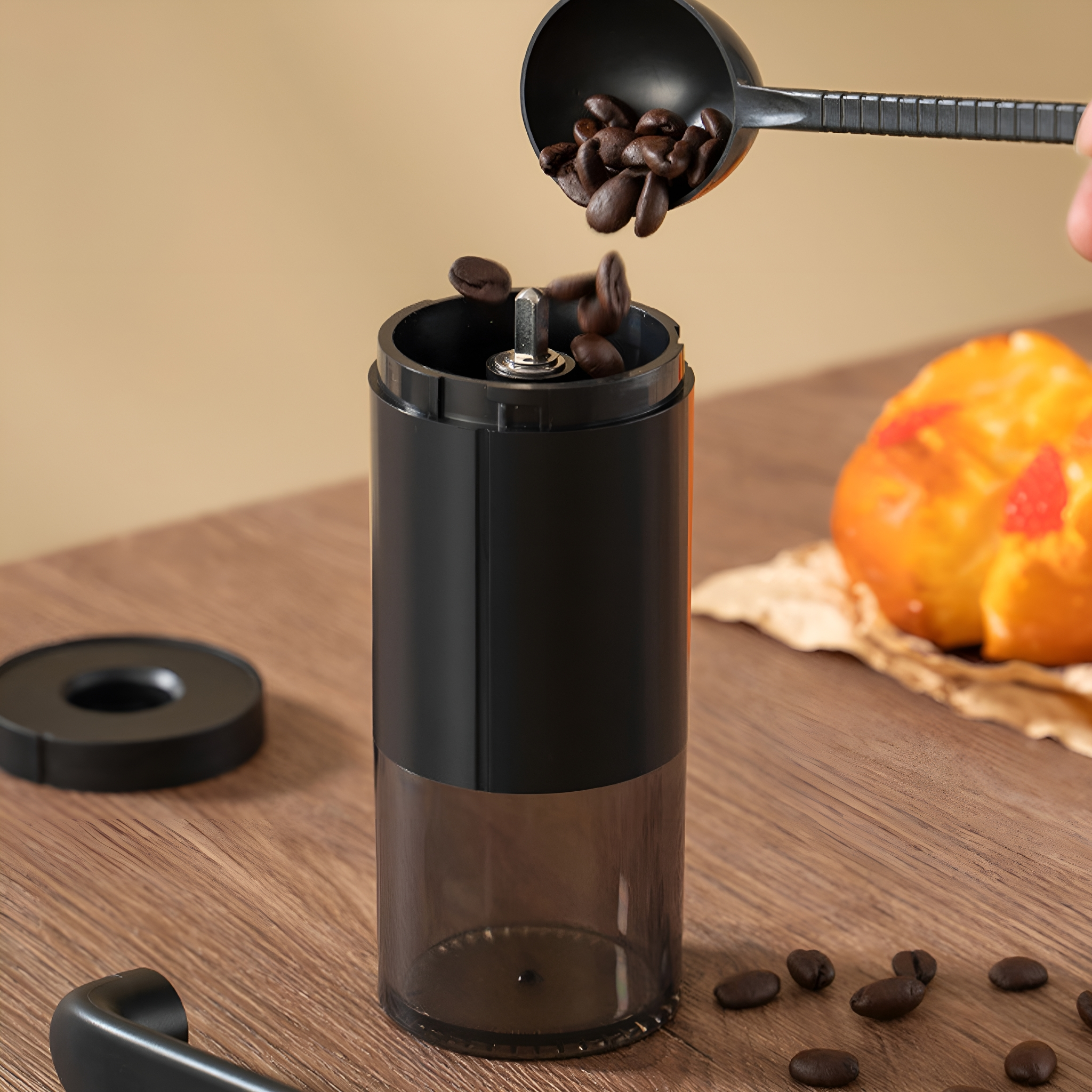 Schwarze Kaffeemühle mit Bohnen, die mit einem schwarzen Löffel eingefüllt werden.