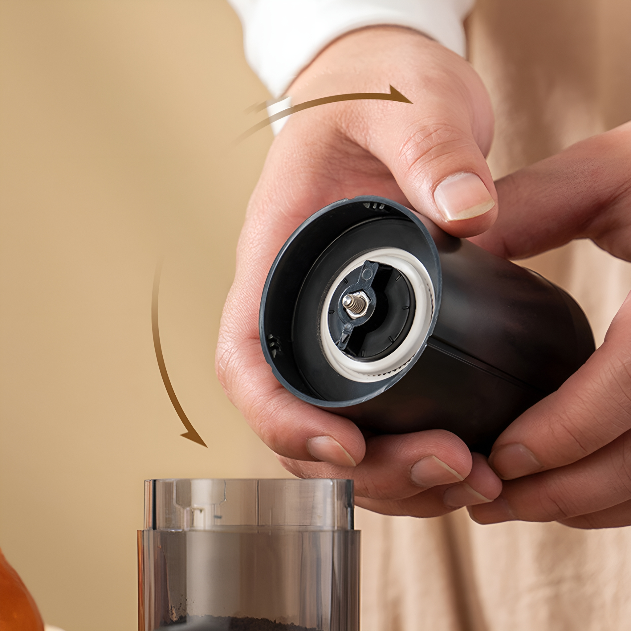 Schwarze Kaffeemühle wird auseinandergenommen. Der Hintergrund ist verschwommen beige.