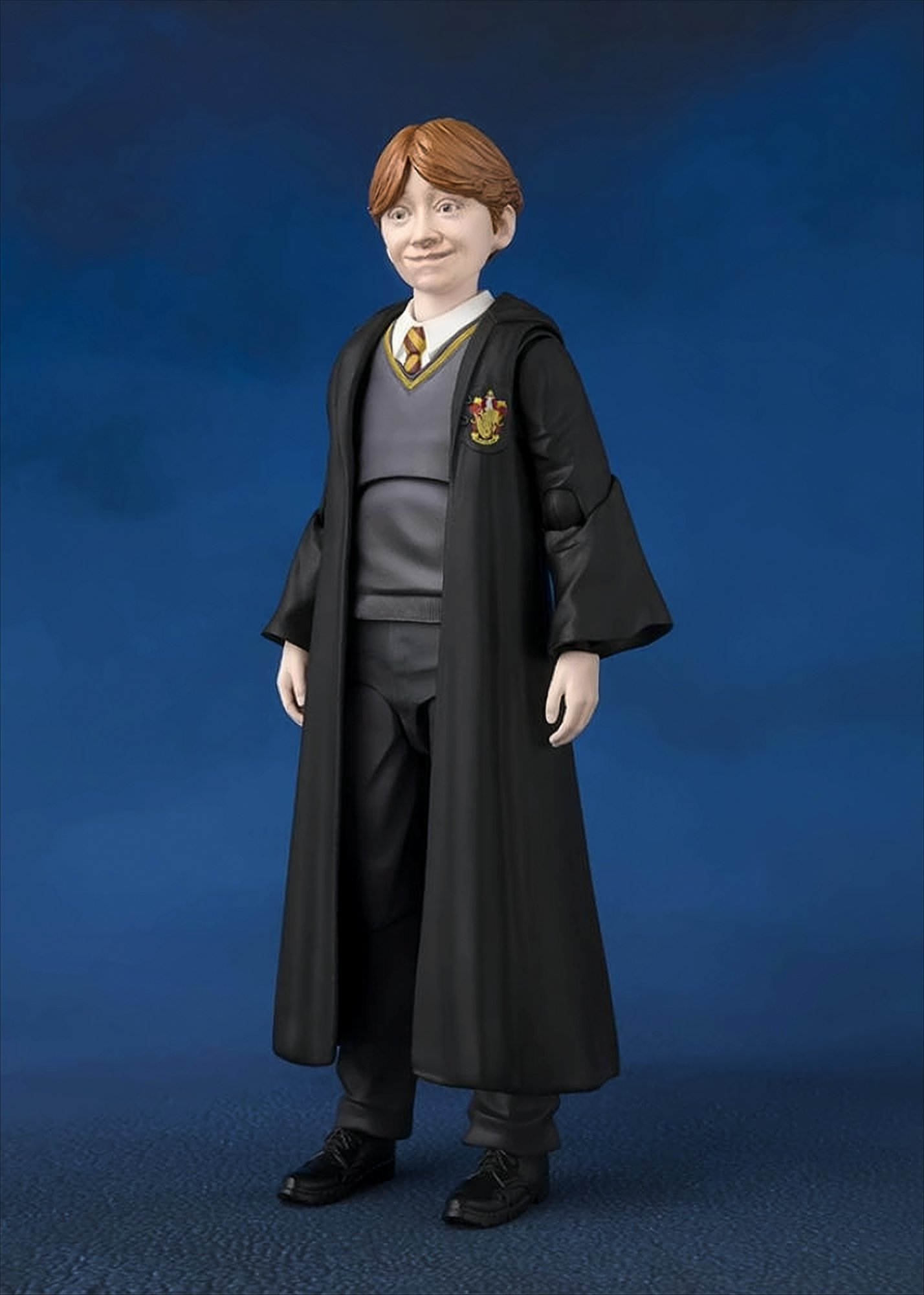 Ron Weasley Actionfigur in einem Zauberer-Umhang. Er steht vor blauem Hintergrund.