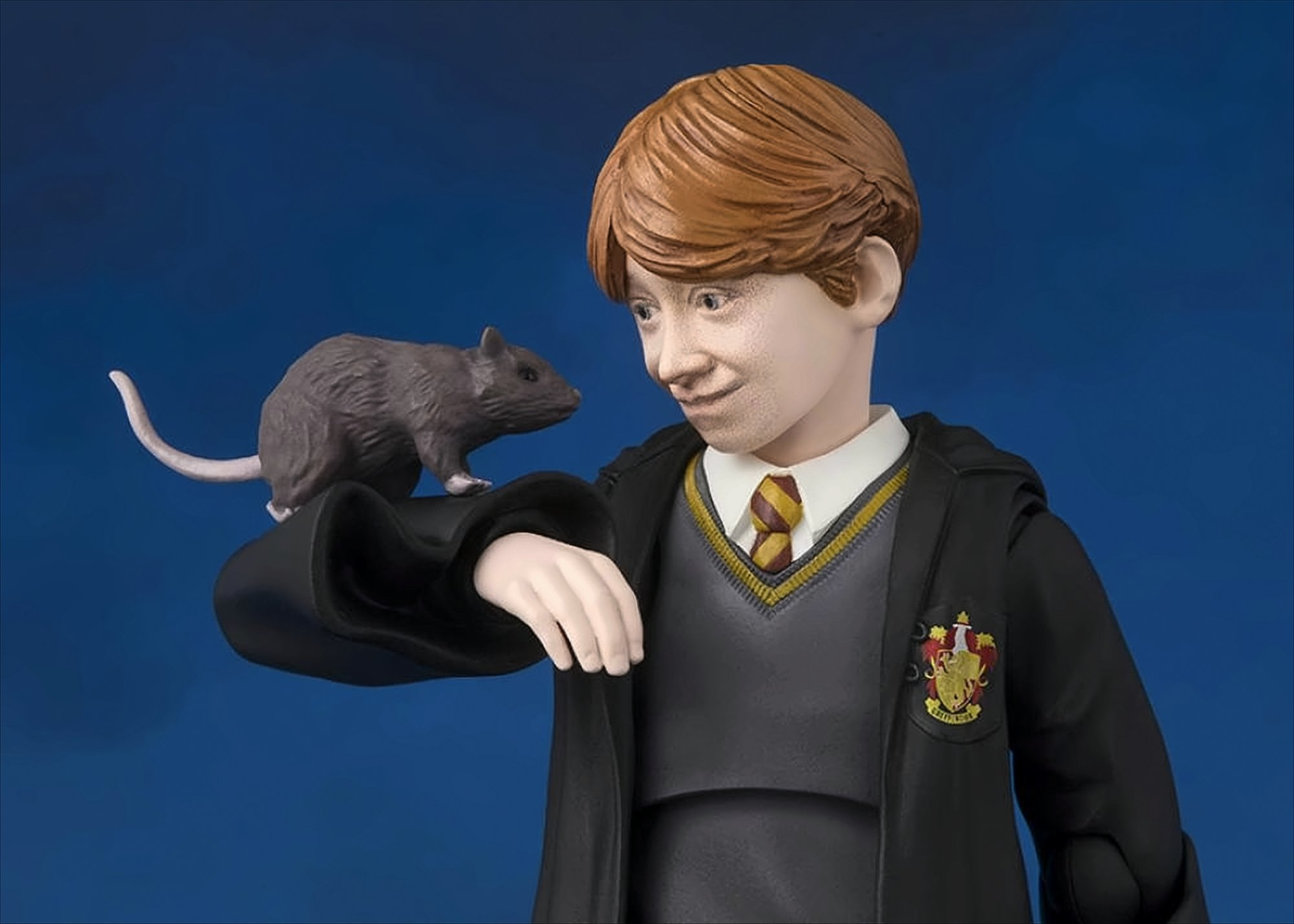 Ron Weasley Figur mit einer Ratte auf dem Arm. Er trägt eine Schuluniform.