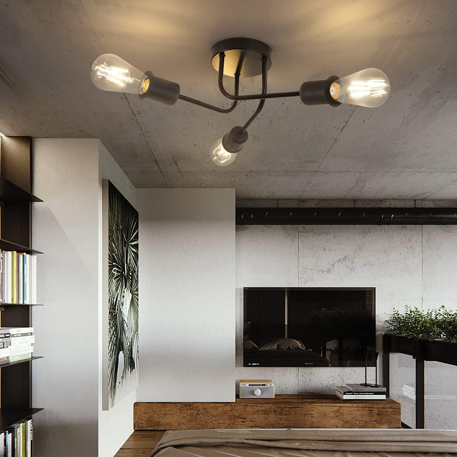 Lampada da soffitto a quattro bulbi con lampadine Edison, contro un muro di cemento e una TV.