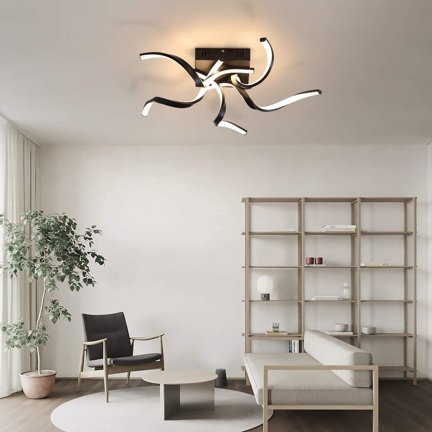 Moderne Deckenleuchte. Schwarzes, geschwungenes Design. Innenraum mit weißen Wänden und Sofa.