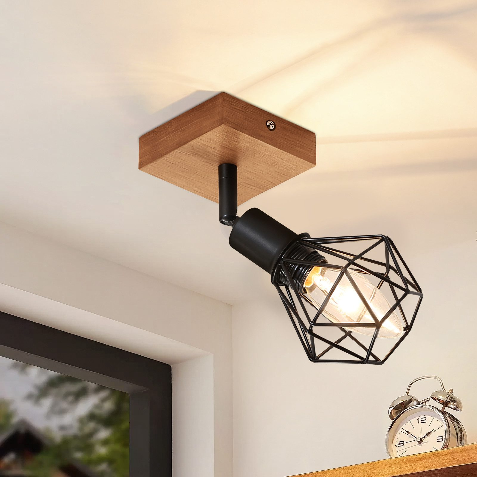 Un faretto da soffitto nero e legno. Ha un paralume a gabbia e una lampadina.