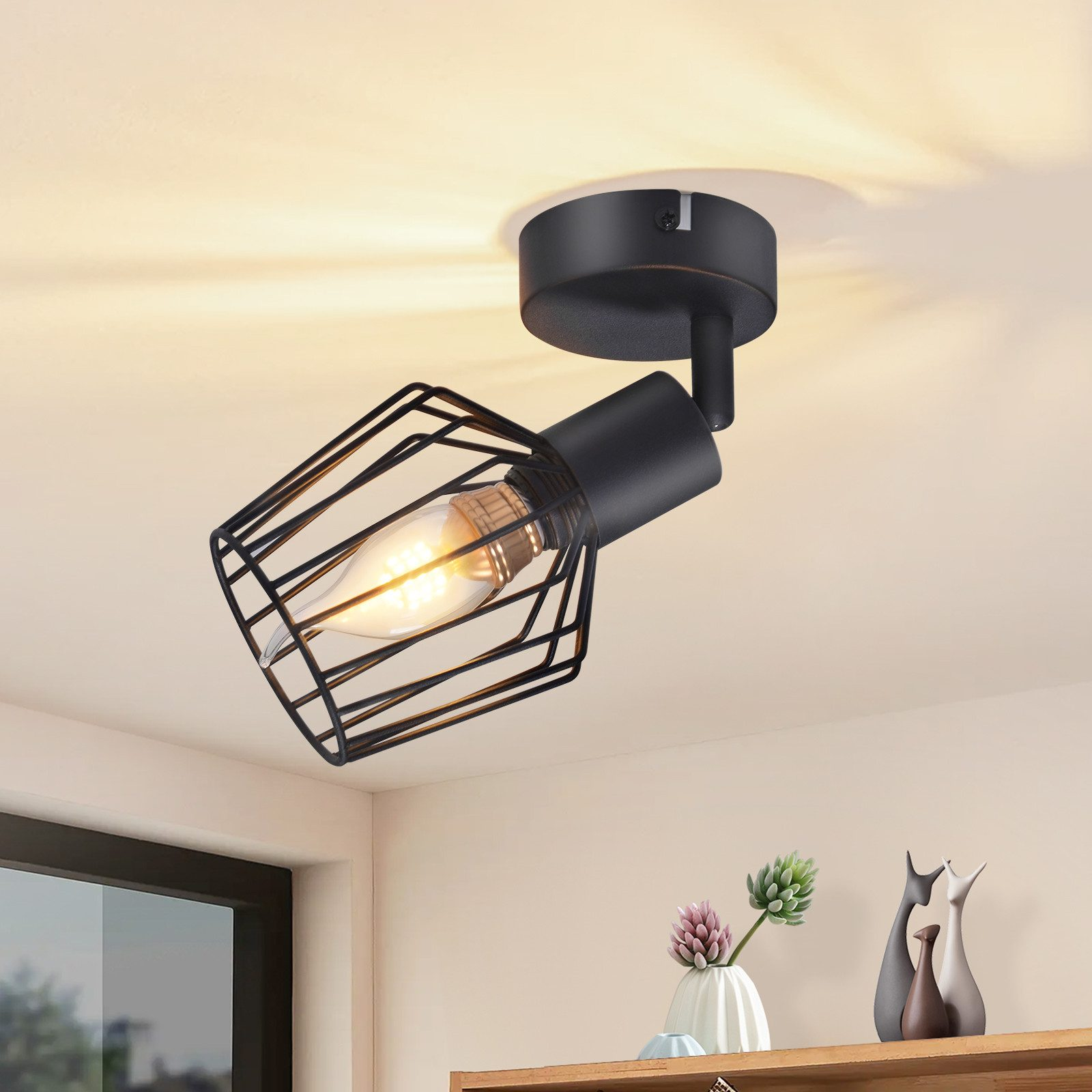 Faretto nero su un soffitto. La luce è diretta verso il basso, con una gabbia decorativa.