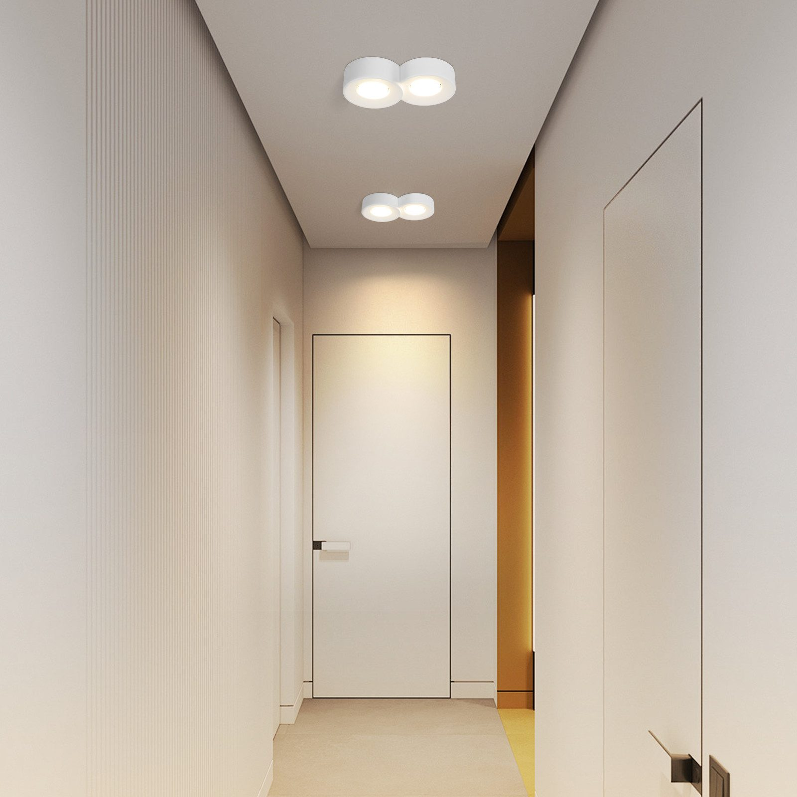 Un corridoio con due lampade da soffitto e pareti e porte bianche. Il corridoio ha un accento dorato.