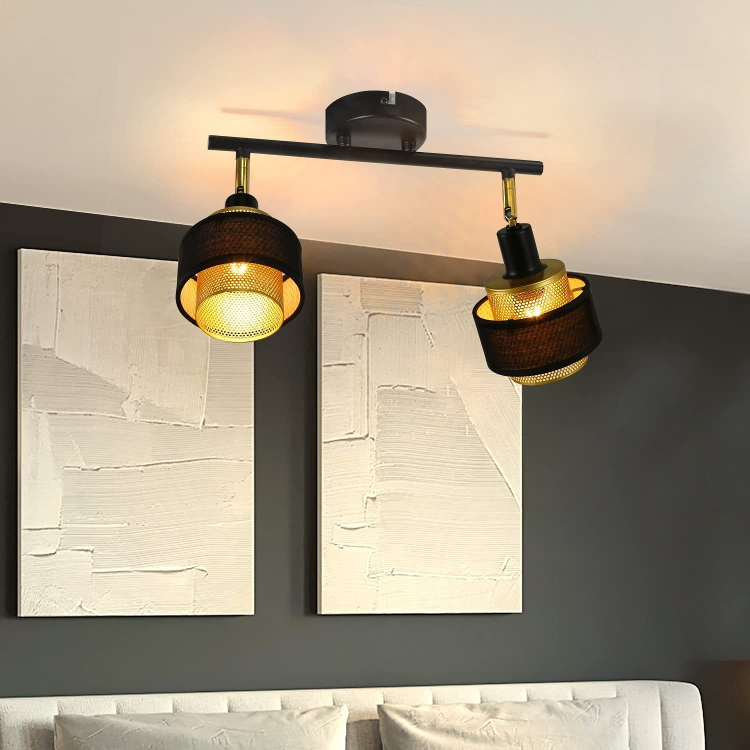 Zwei schwarze und goldene Scheinwerfer an einer schwarzen Schiene, an einer weißen Wand montiert.
