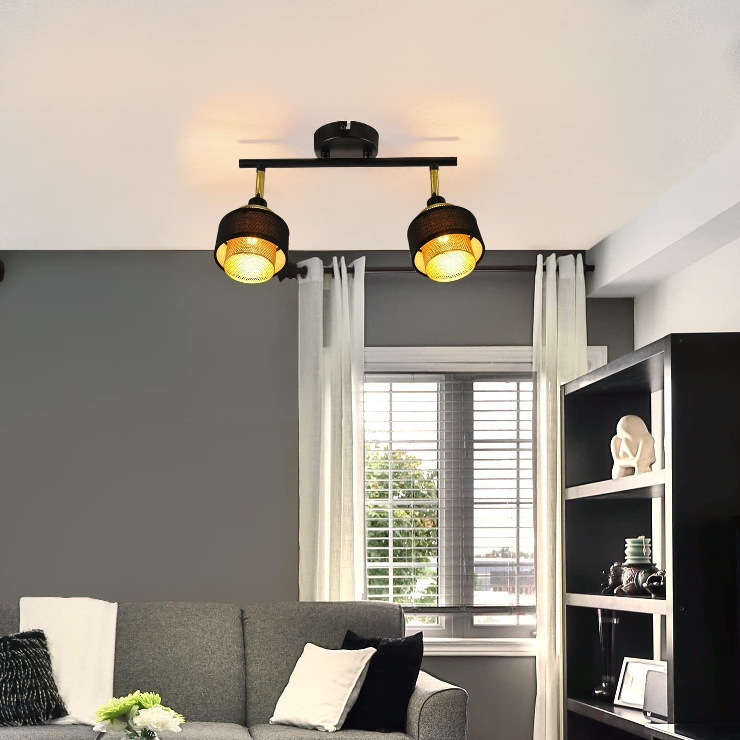 Ein Wohnzimmer mit grauem Sofa, Strahlern und einem schwarzen Regal mit Deko.