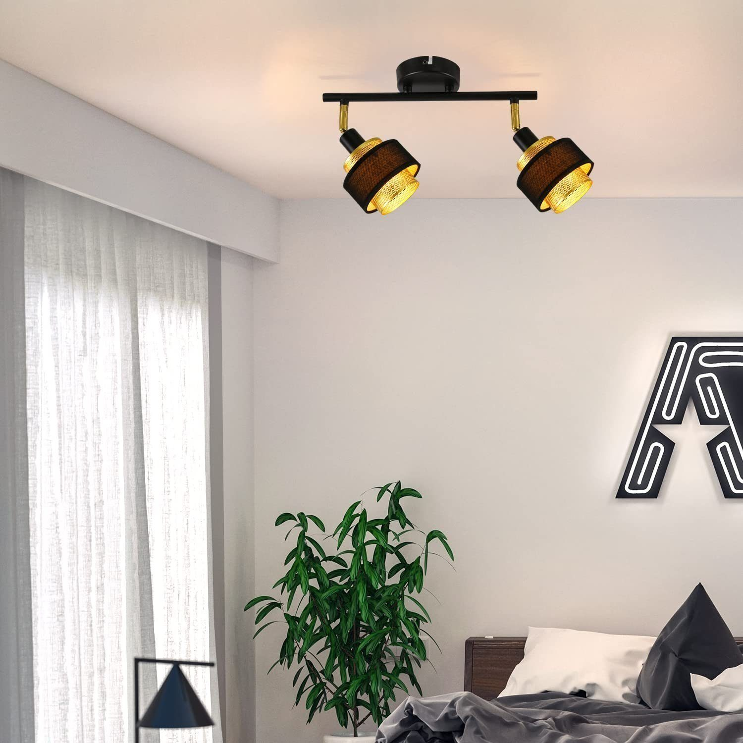 Schlafzimmer mit zwei Strahlern, einer Pflanze und einem Neon-Buchstaben 'A' an der Wand.