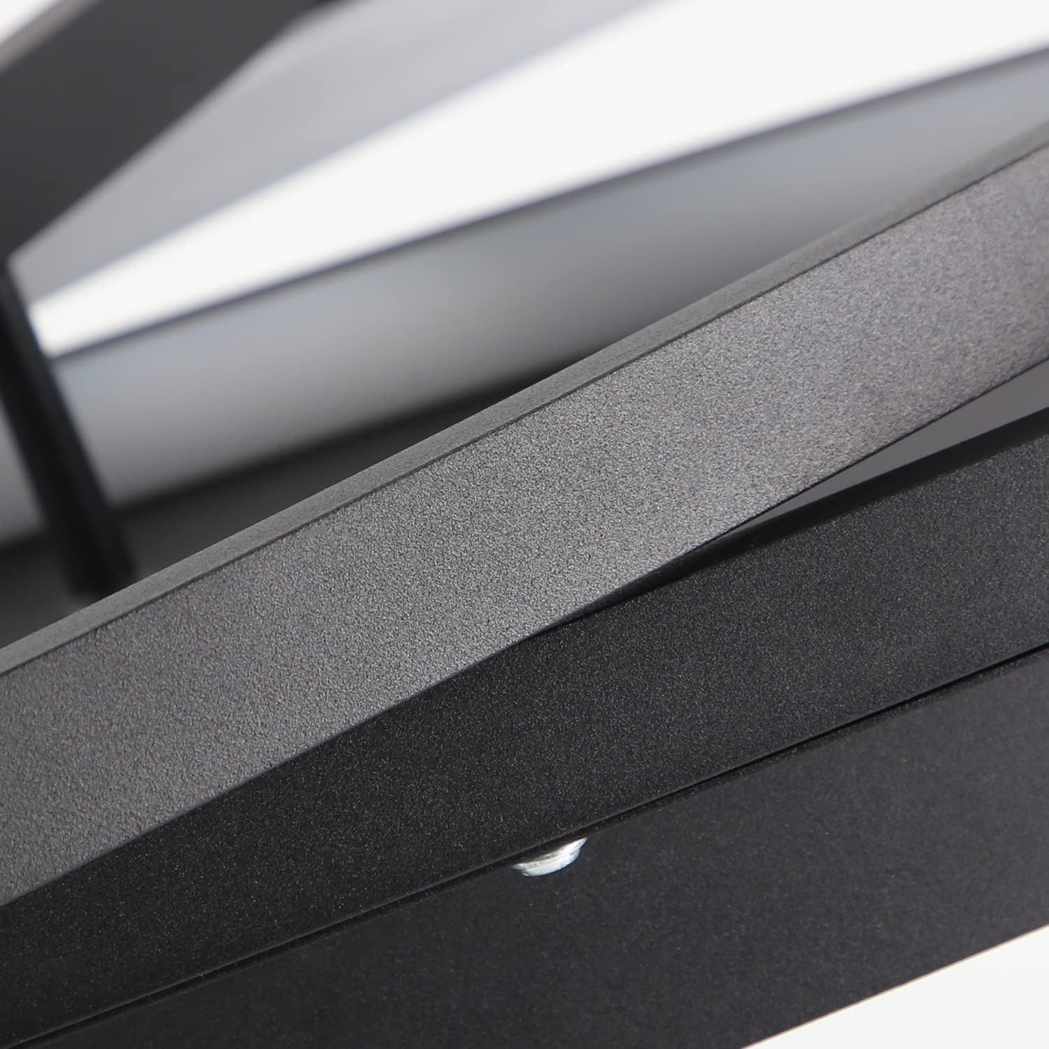 Zbliżenie czarnej metalowej konstrukcji. Metal jest teksturowany. Tło jest jasnoszare.