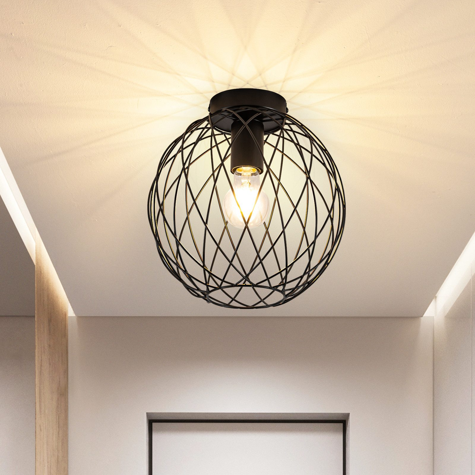 Una plafoniera nera con design a gabbia di filo e una lampadina visibile.