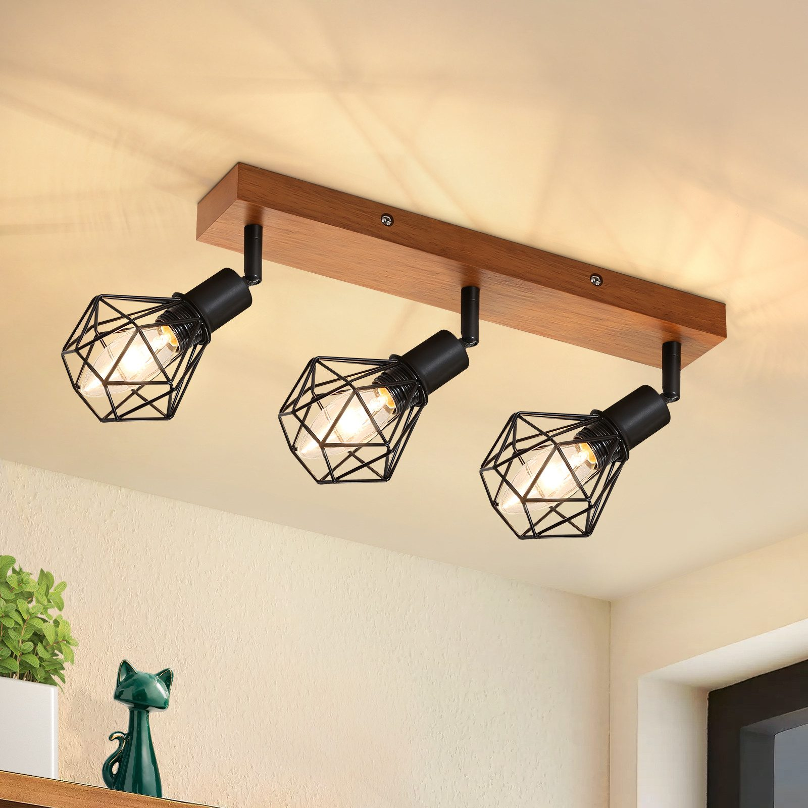 Soffitto con tre faretti neri su una trave di legno, sopra un muro color crema.