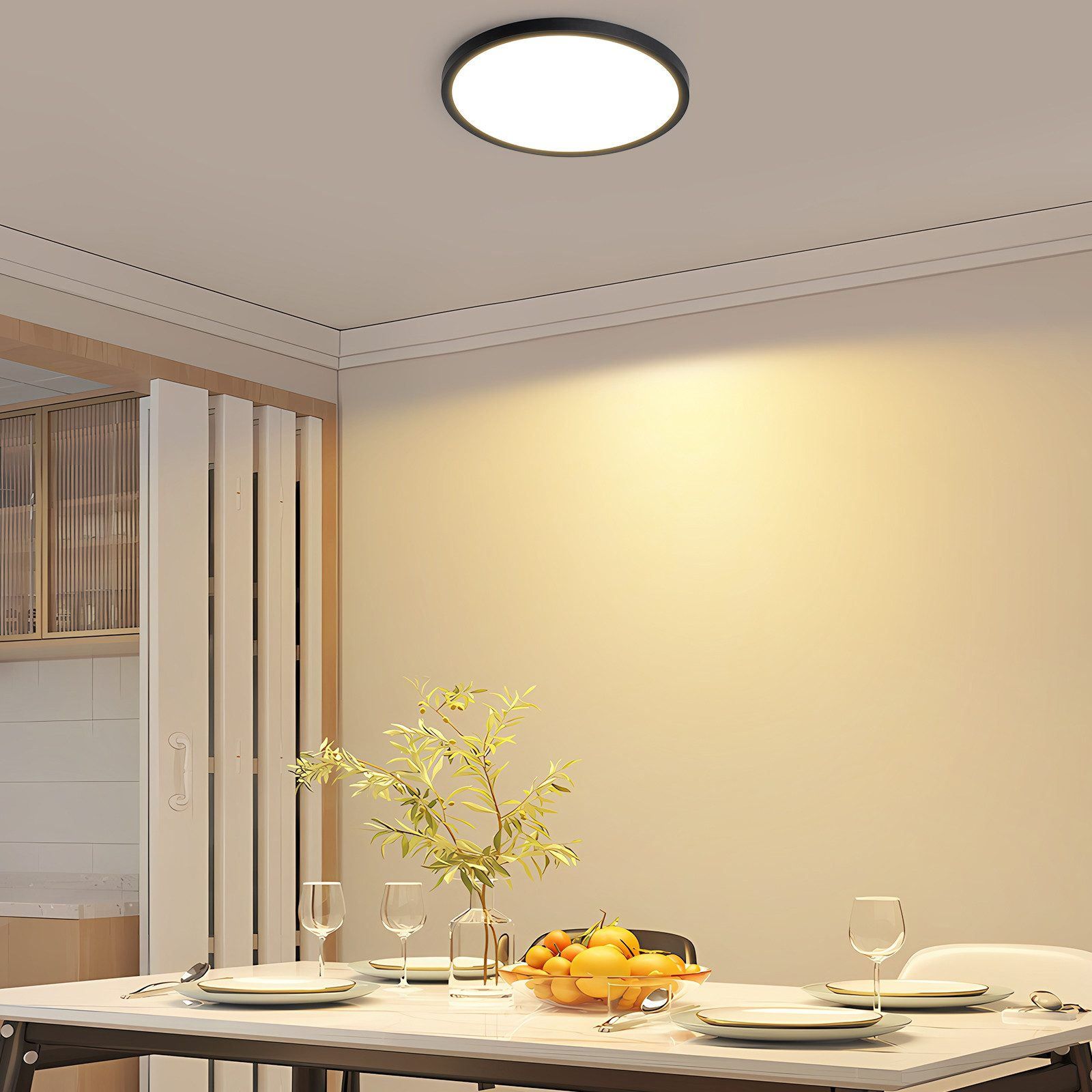 Una sala da pranzo con una luce a soffitto rotonda, tavolo apparecchiato con piatti e un vaso di fiori.