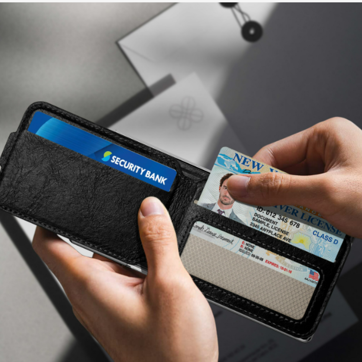 Mani che tengono un portafoglio nero con due carte. Una carta con foto viene rimossa.