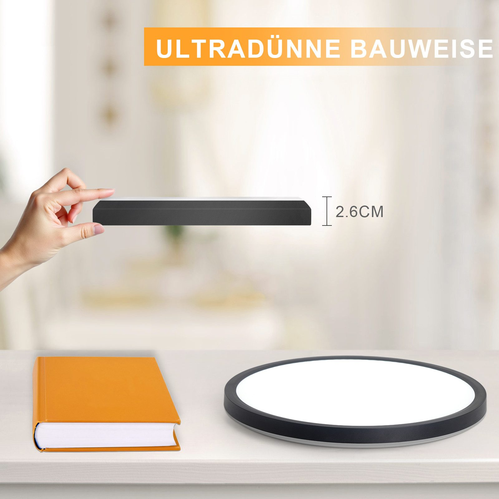 Una mano tiene un apparecchio di illuminazione nero sottile. Un libro e una luce rotonda sono su un tavolo.