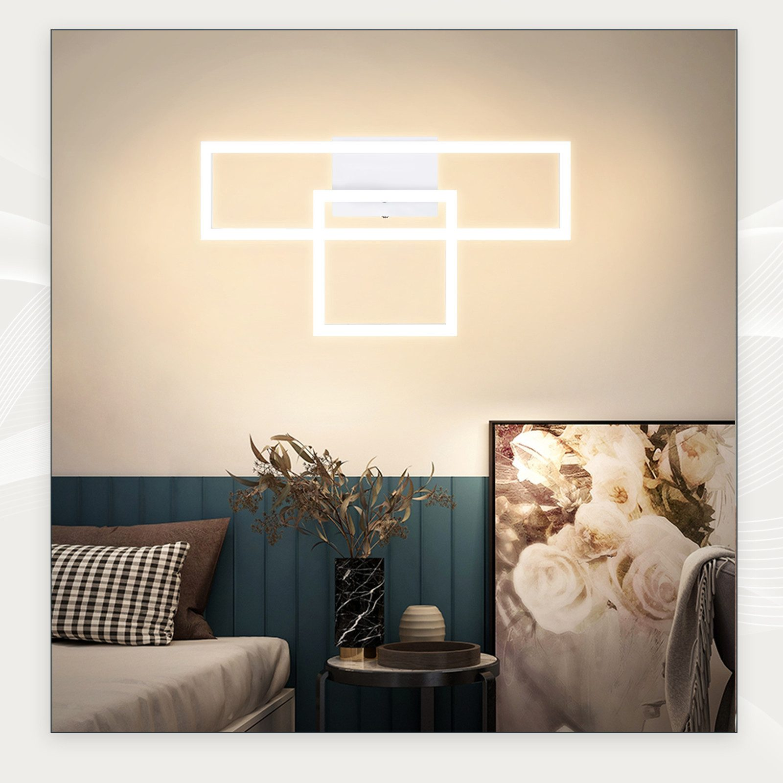 Eine weiße Wandleuchte mit drei rechteckigen Lichtern. An der Wand befinden sich ein Gemälde und Dekorationen.