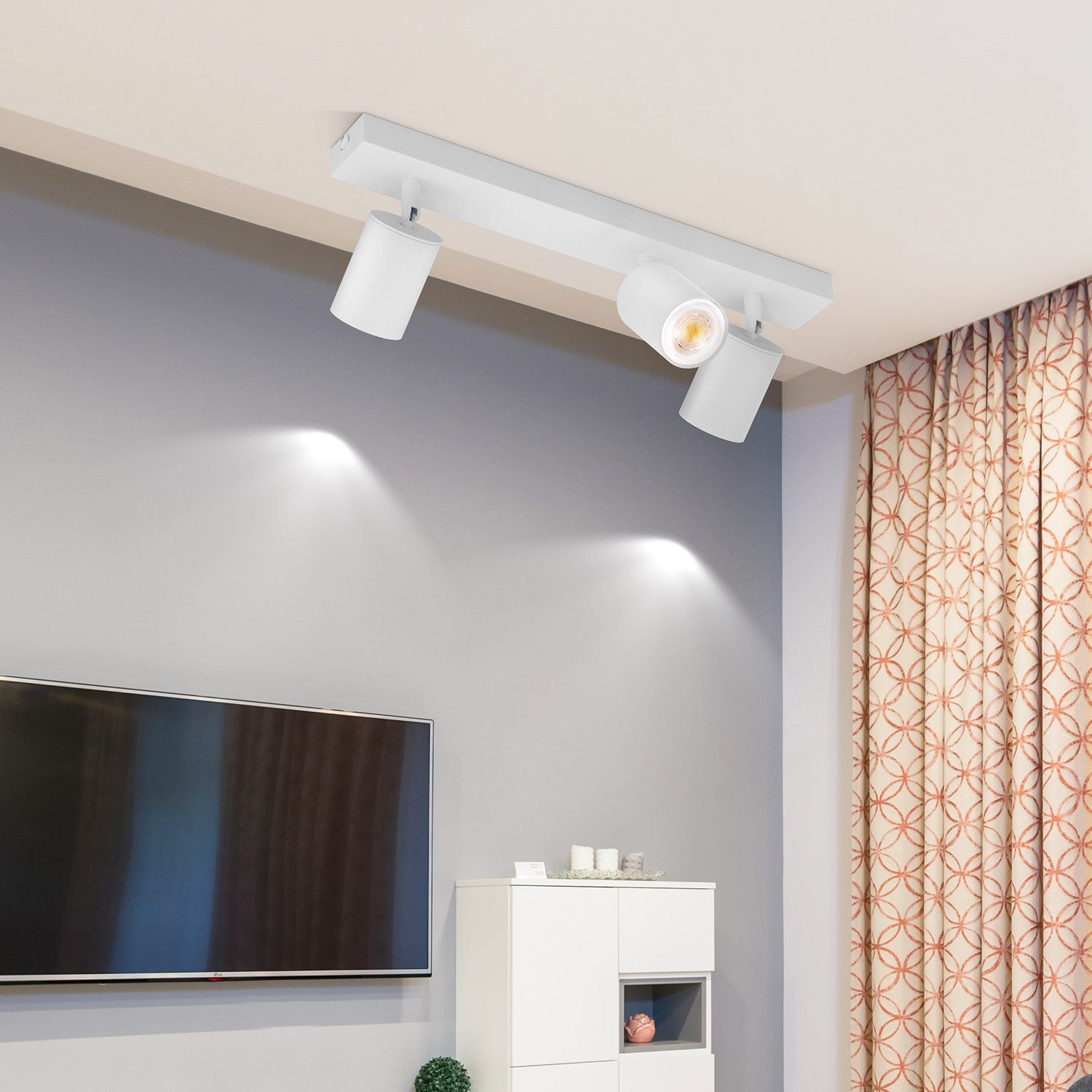 Tre faretti bianchi montati su una guida bianca sul soffitto, con fasci di luce diretti verso il basso.