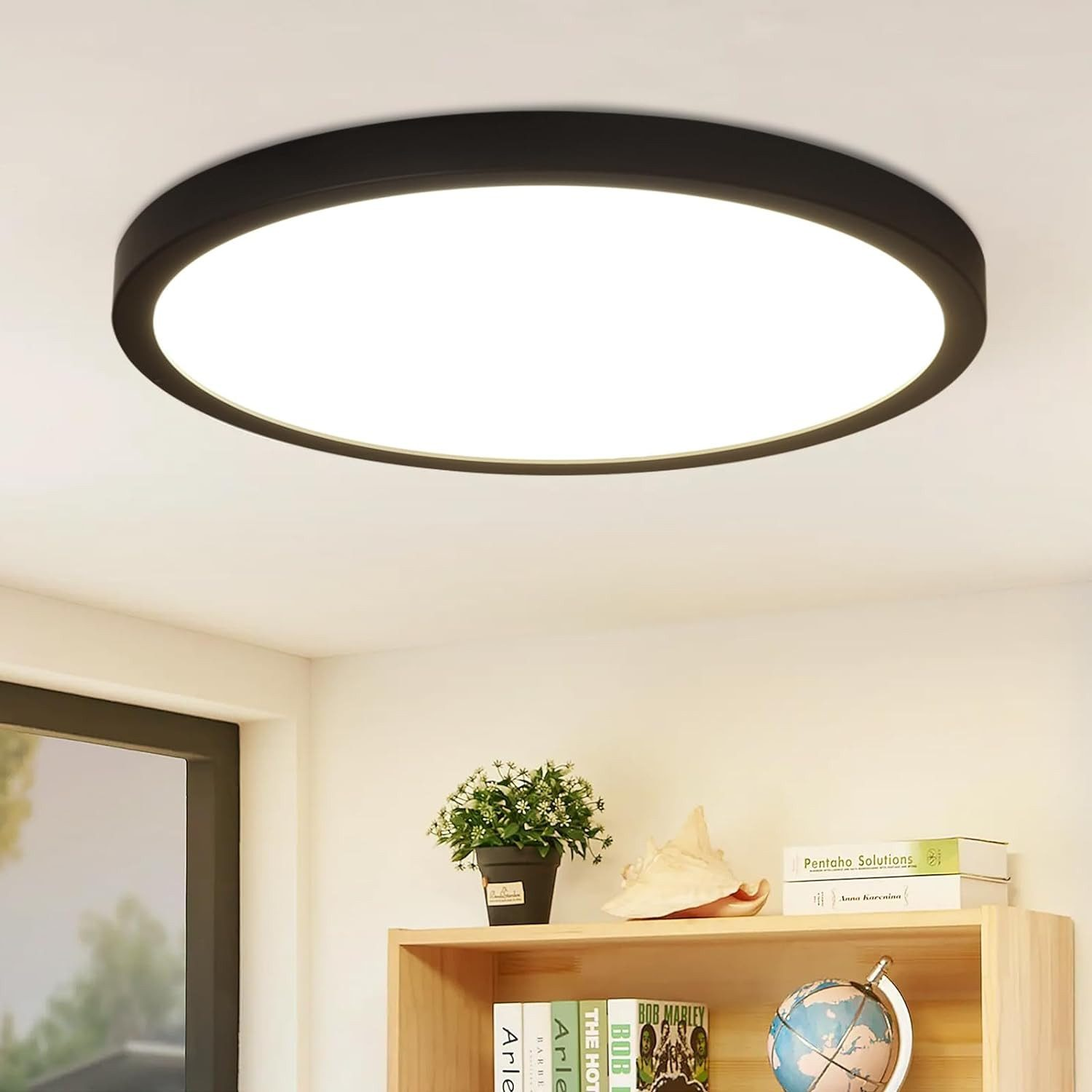 Una luce a soffitto rotonda con cornice nera, installata su un soffitto bianco. Mensola con decorazioni.