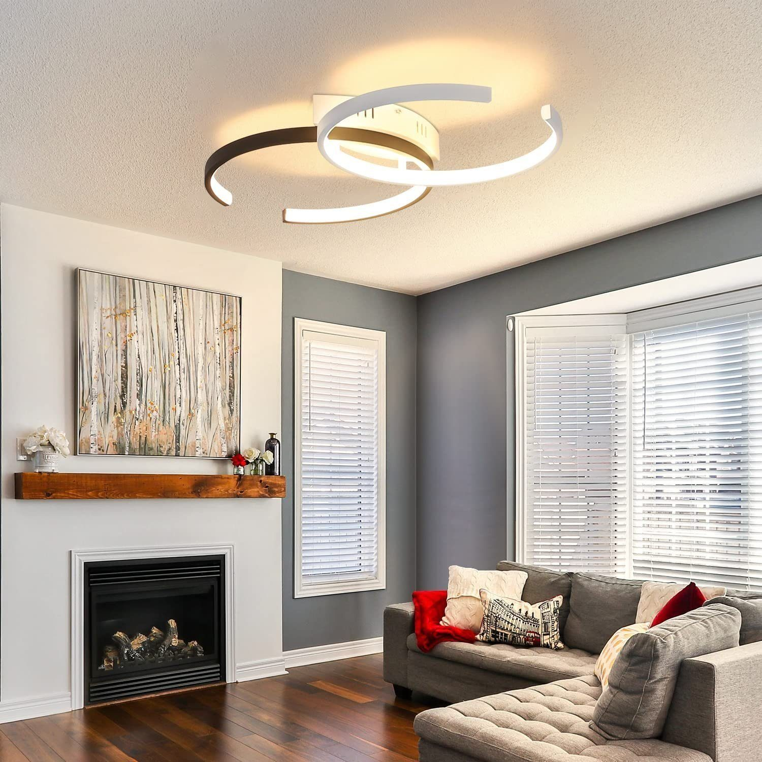 Lampada da soffitto moderna, divano grigio con cuscini rossi, camino e finestra con persiane.