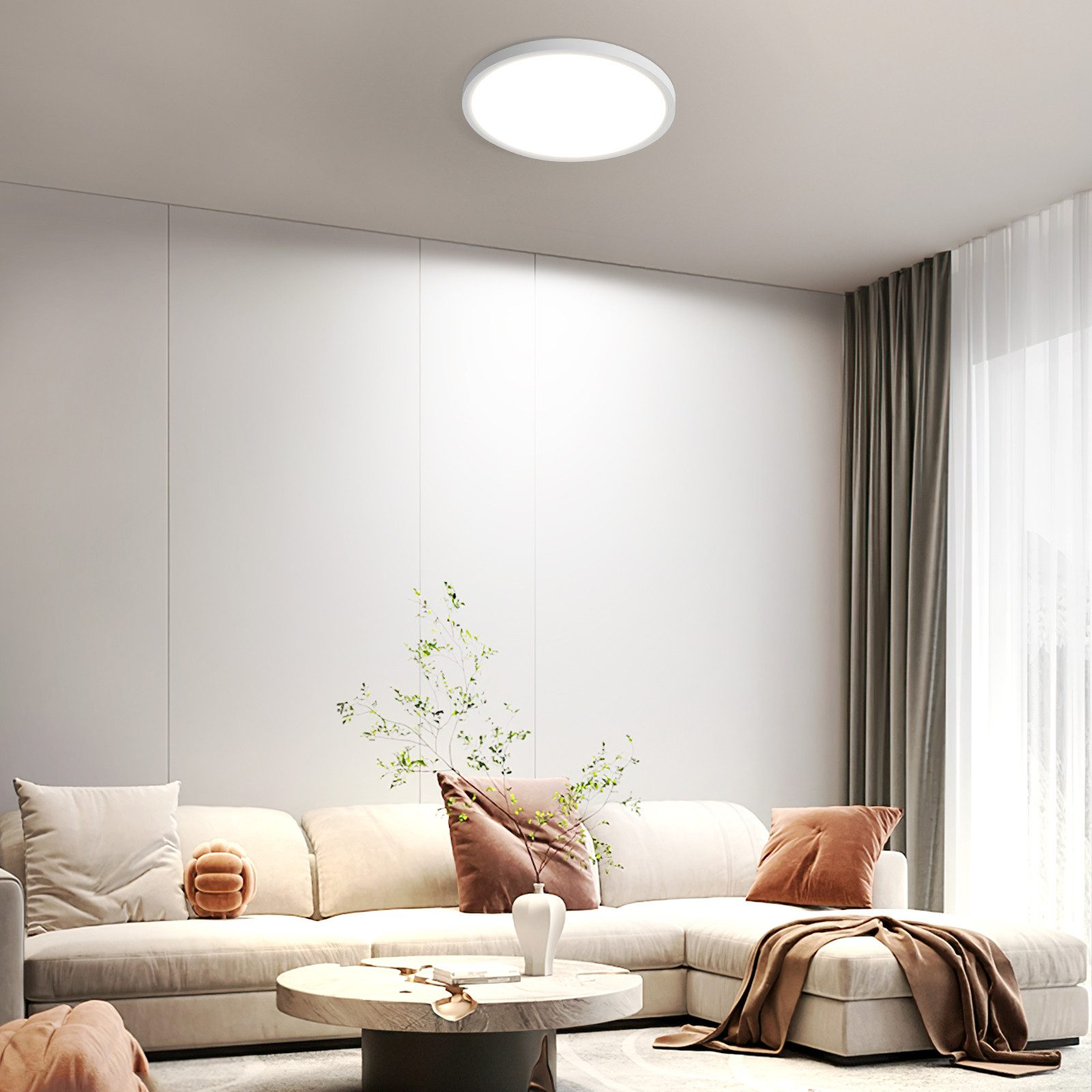 Un soggiorno moderno con una luce a soffitto bianca, un divano beige e cuscini color terra.