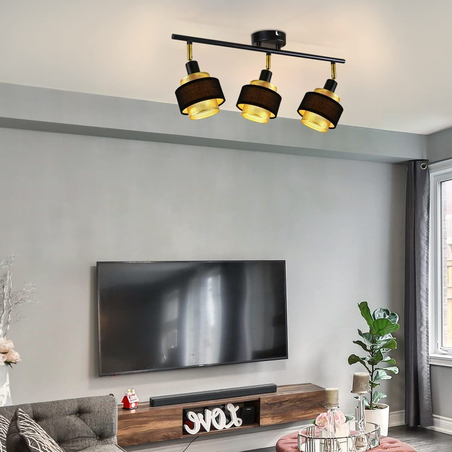 Soggiorno con faretti, TV, mobile in legno e piante. Il muro è dipinto di grigio.