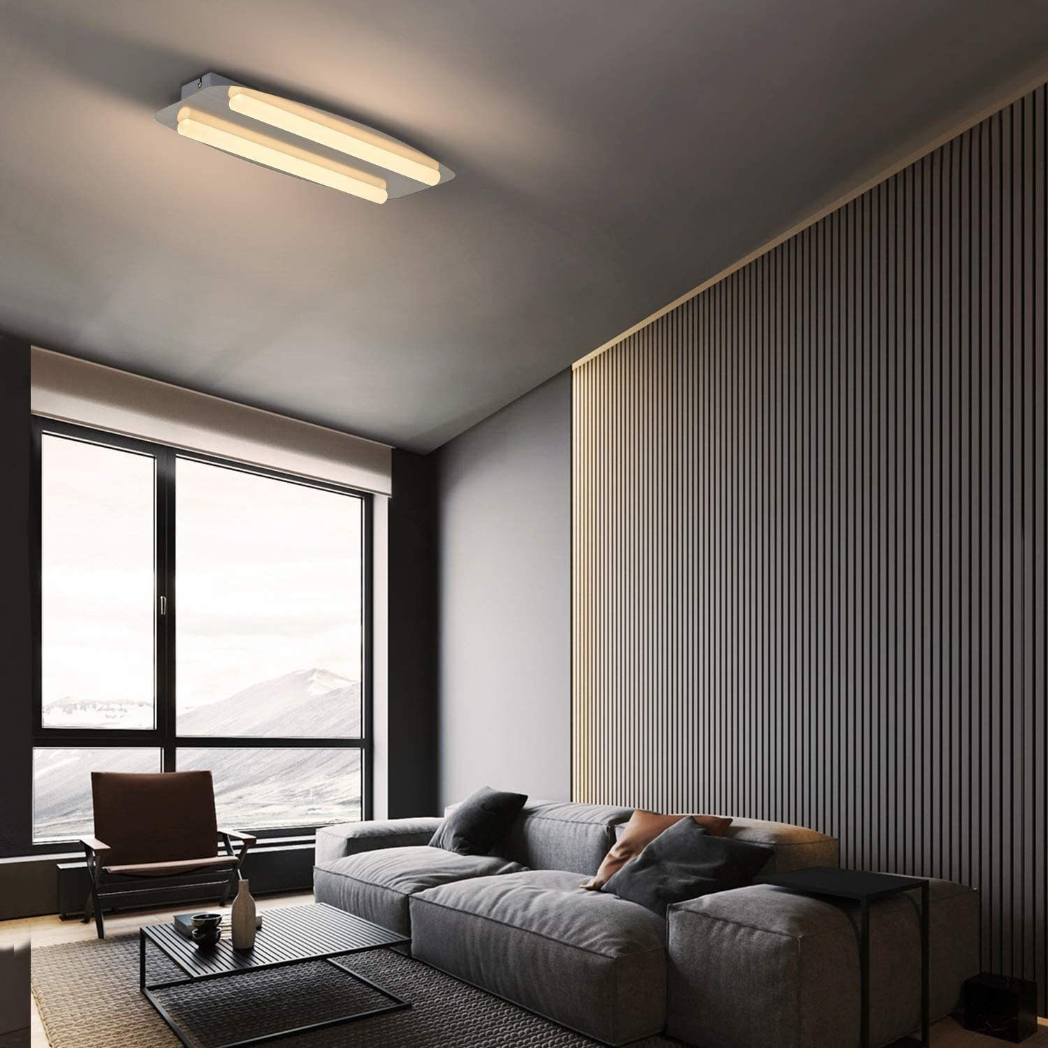 Un moderno soggiorno con una grande finestra, un divano grigio e una luce a soffitto minimalista.