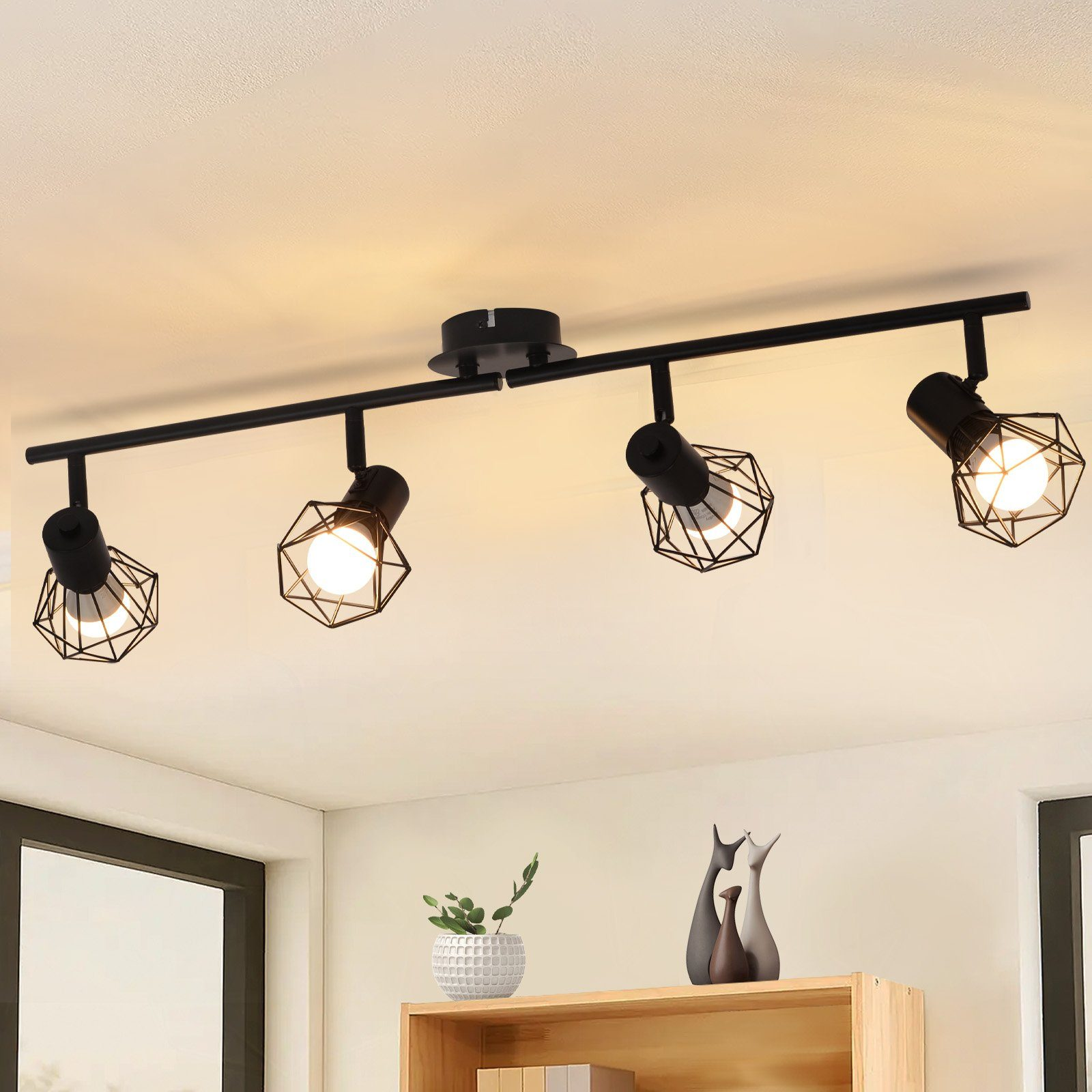 Czarne oświetlenie szynowe z czterema geometrycznymi lampami, półka z dekoracjami.