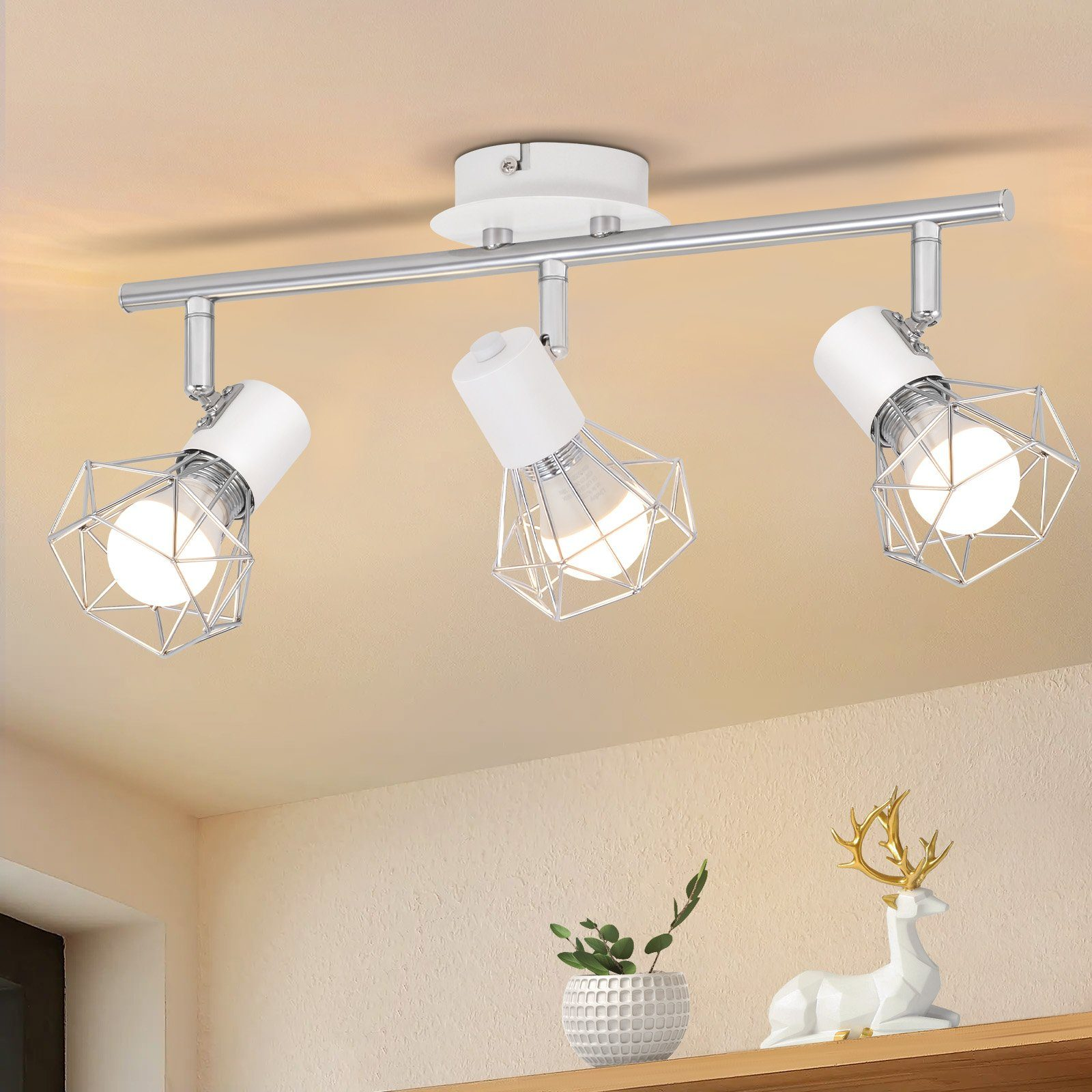 Tre luci a soffitto con gabbie di filo geometriche. Appendono da una pista. Interior design con decorazioni.