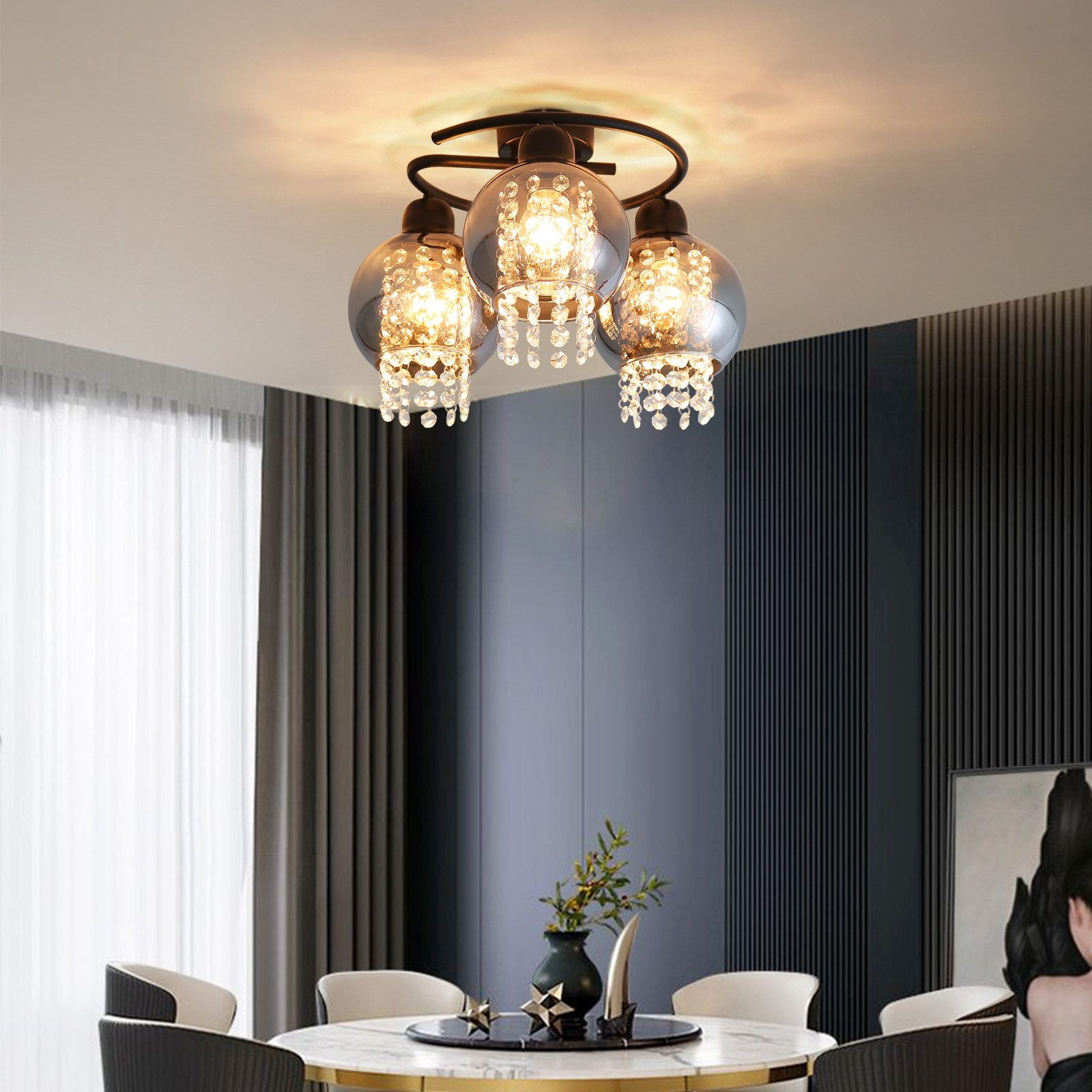 Lampa sufitowa z trzema kryształowymi szklanymi kulami. Pokój ma ciemną ścianę i okrągły stół.