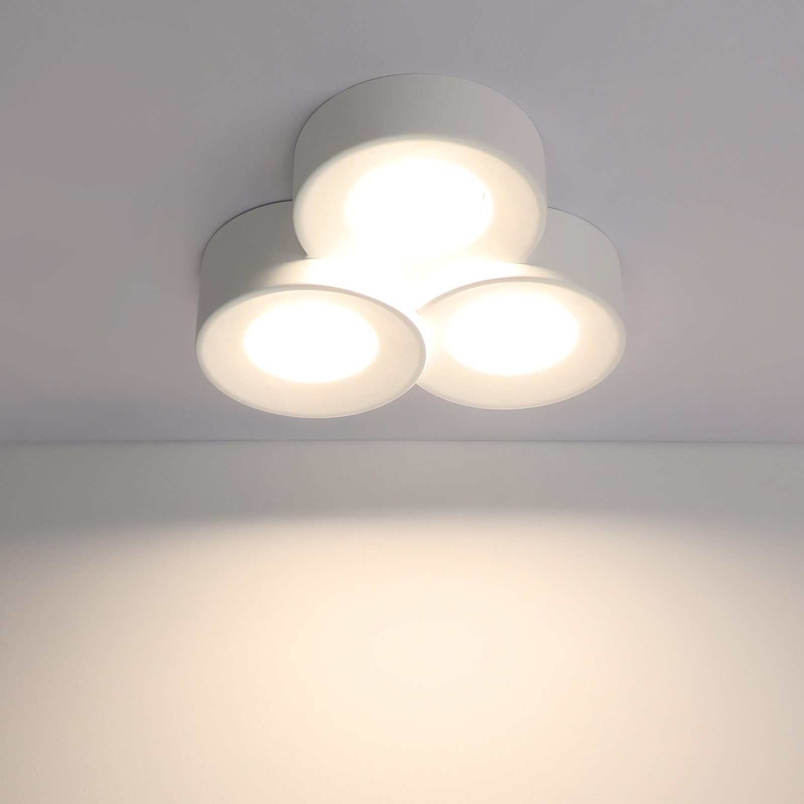 Soffitto con tre luci bianche, circolari, ognuna emette luce intensa.