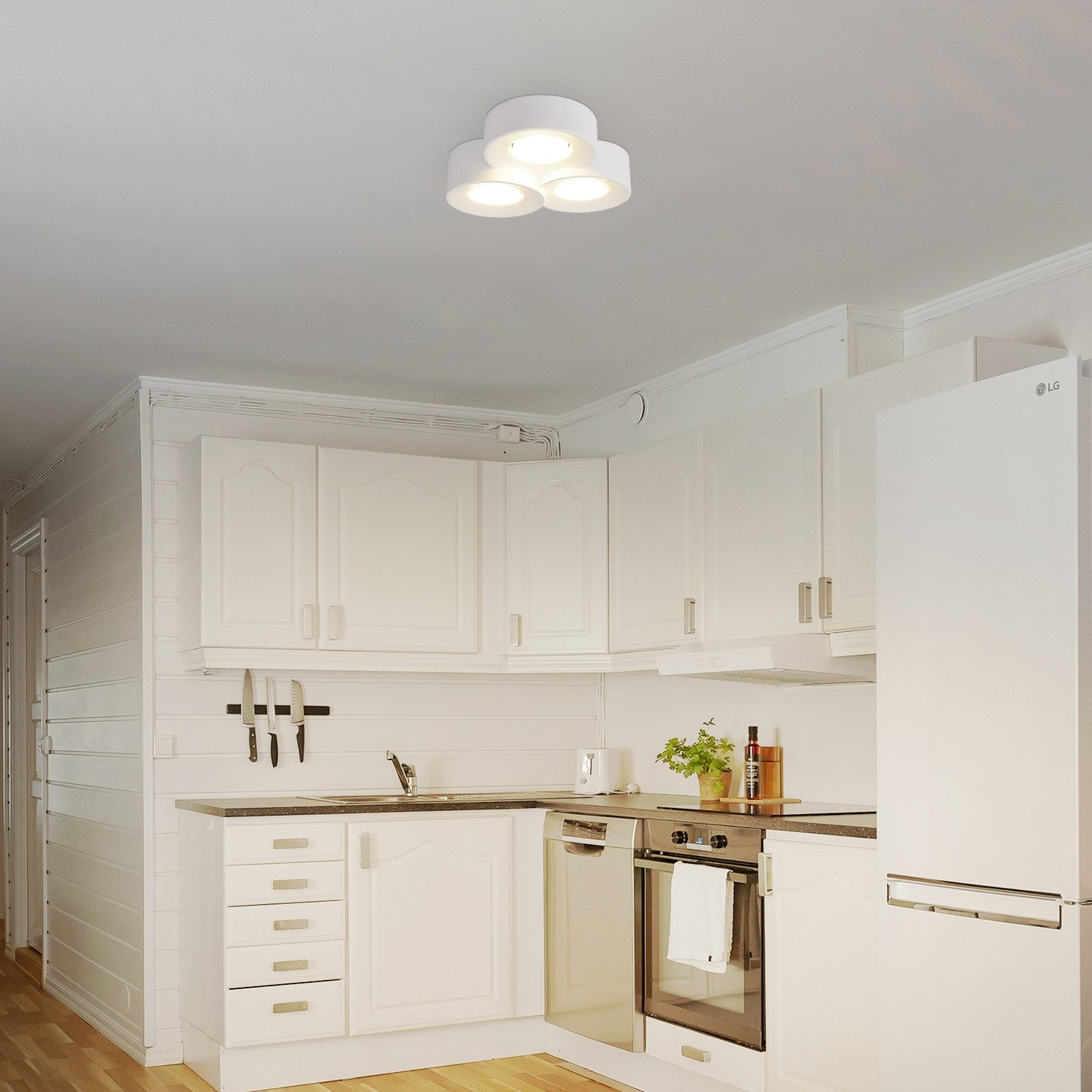 Una cucina moderna con mobili bianchi, un lavello e elettrodomestici in acciaio inossidabile e illuminazione a incasso.