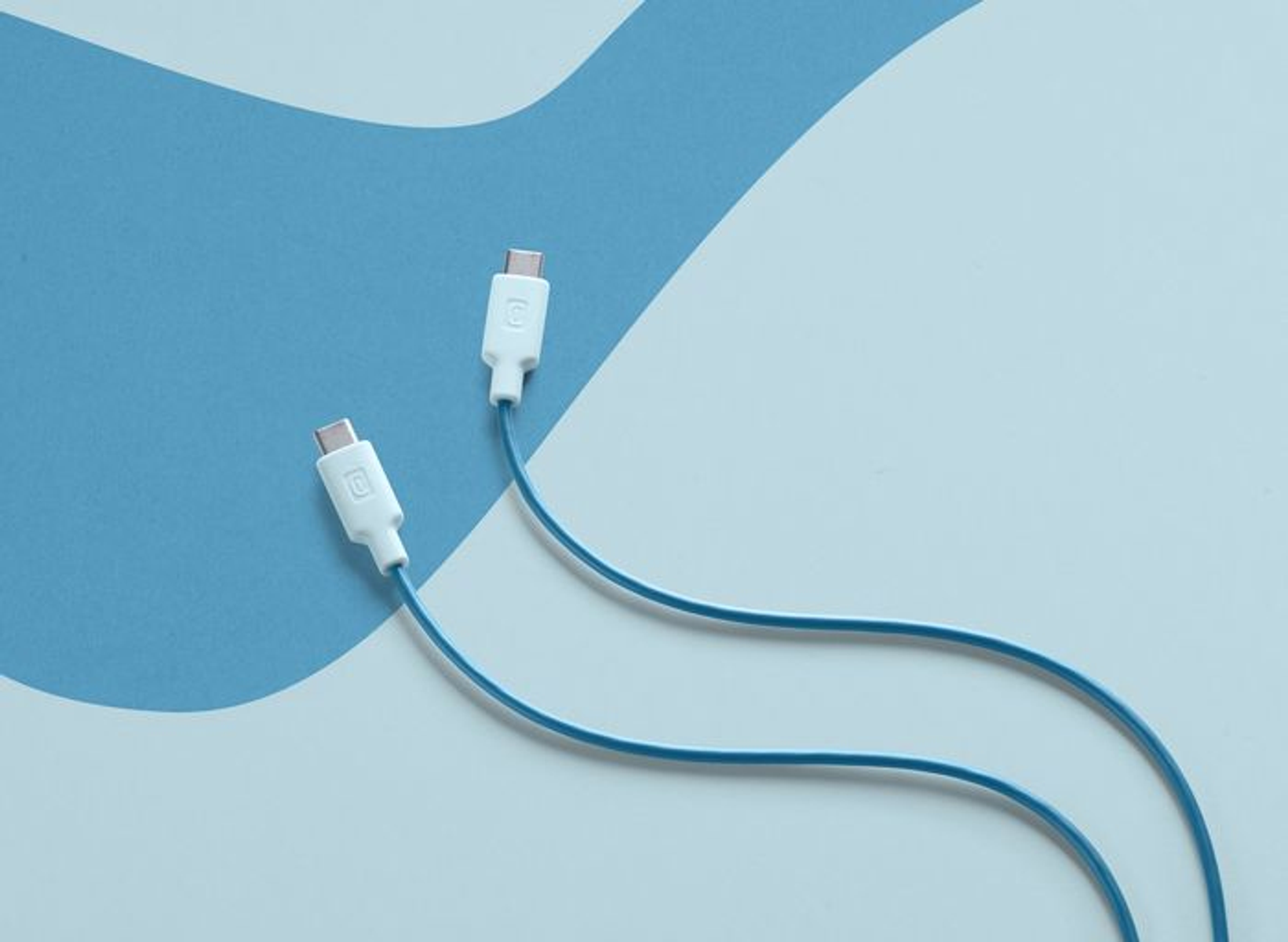 Dos cables USB-C con conectores blancos y cables azules sobre fondo azul.