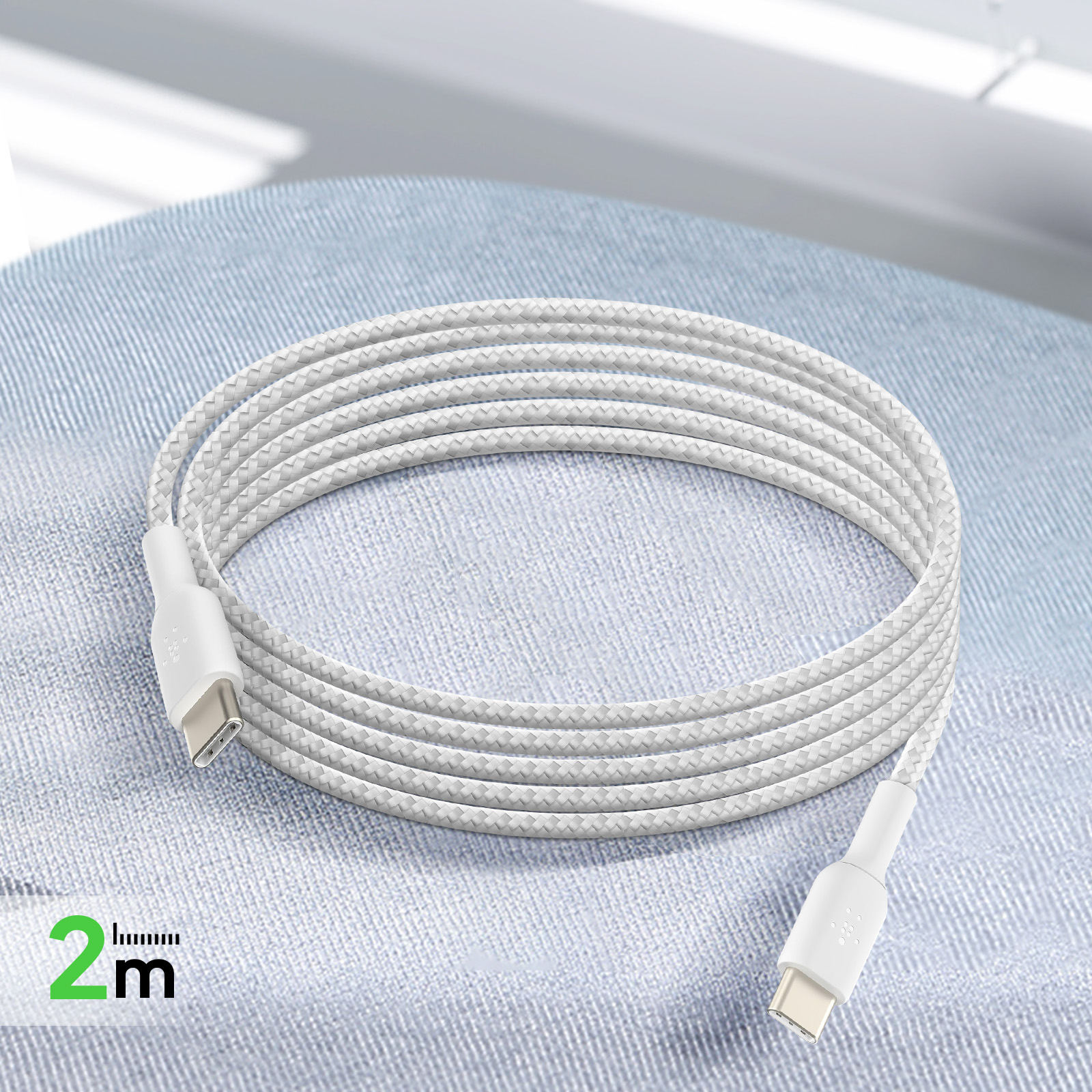 Un câble USB-C blanc est enroulé sur un tissu bleu.
