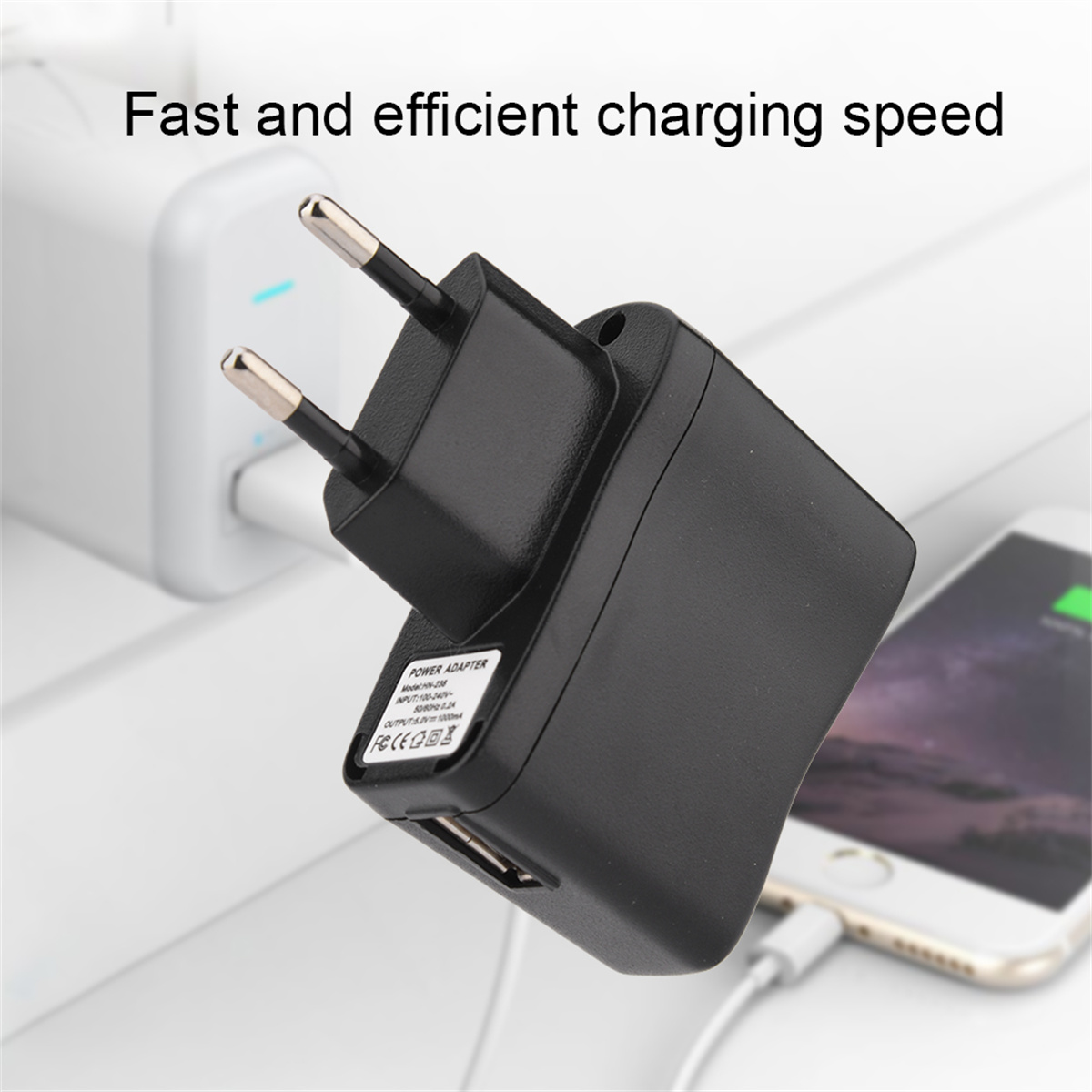 Ein schwarzer Netzadapter mit Stiften, der in einer Steckdose steckt. Ein Telefon ist über ein weißes Kabel verbunden.